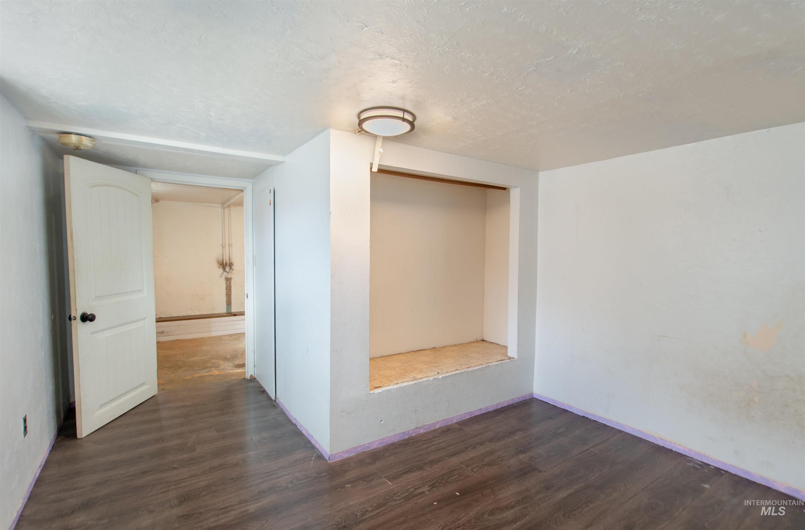 Spare room featuring dark wood-style flooring and a textured ceiling