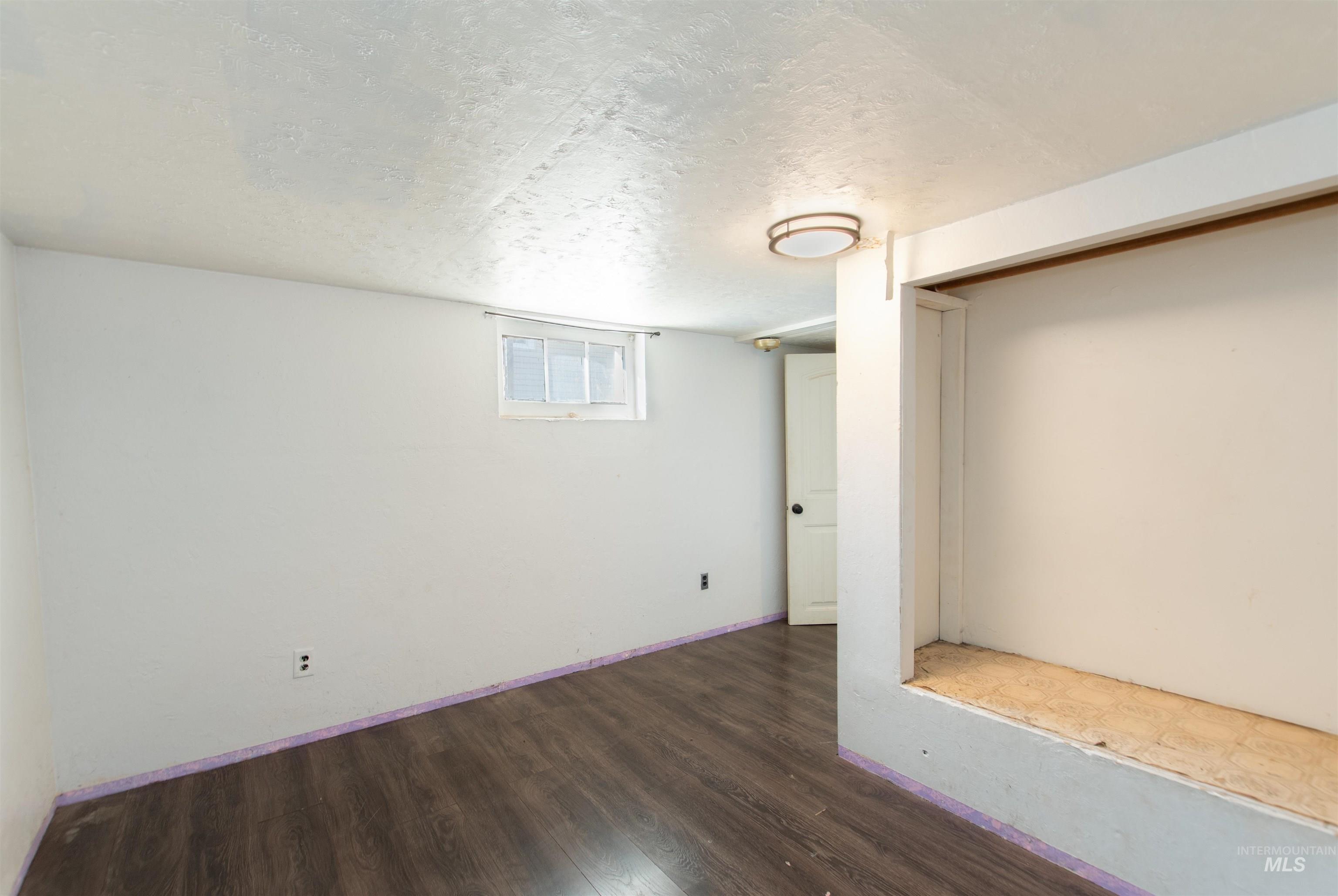 Basement featuring a textured ceiling and dark wood-style flooring