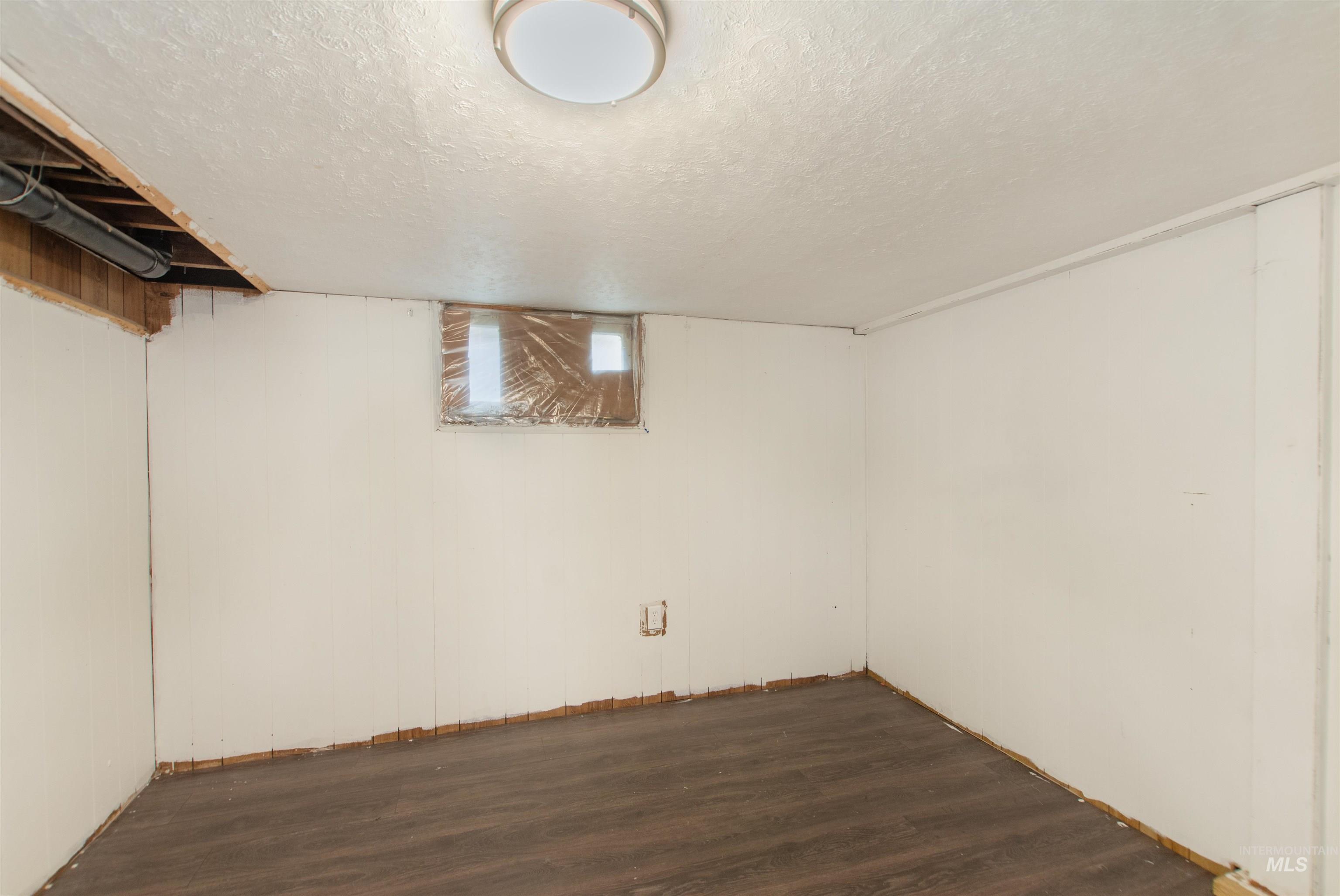 Finished below grade area featuring a textured ceiling and dark wood finished floors