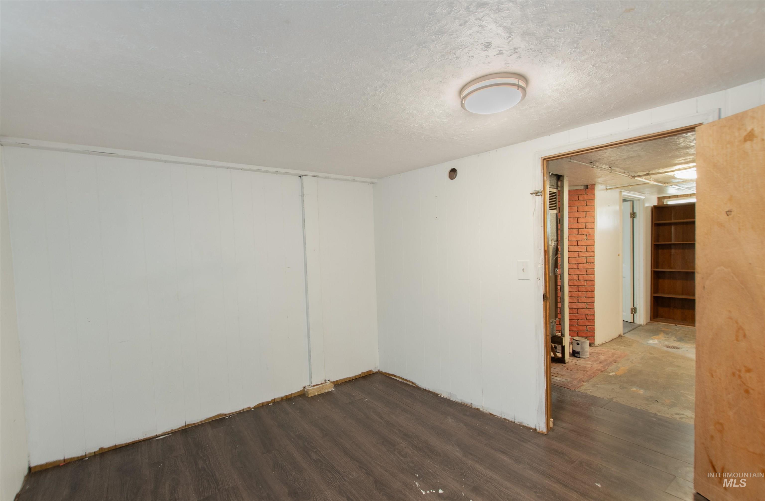 Empty room with a textured ceiling and dark wood-type flooring