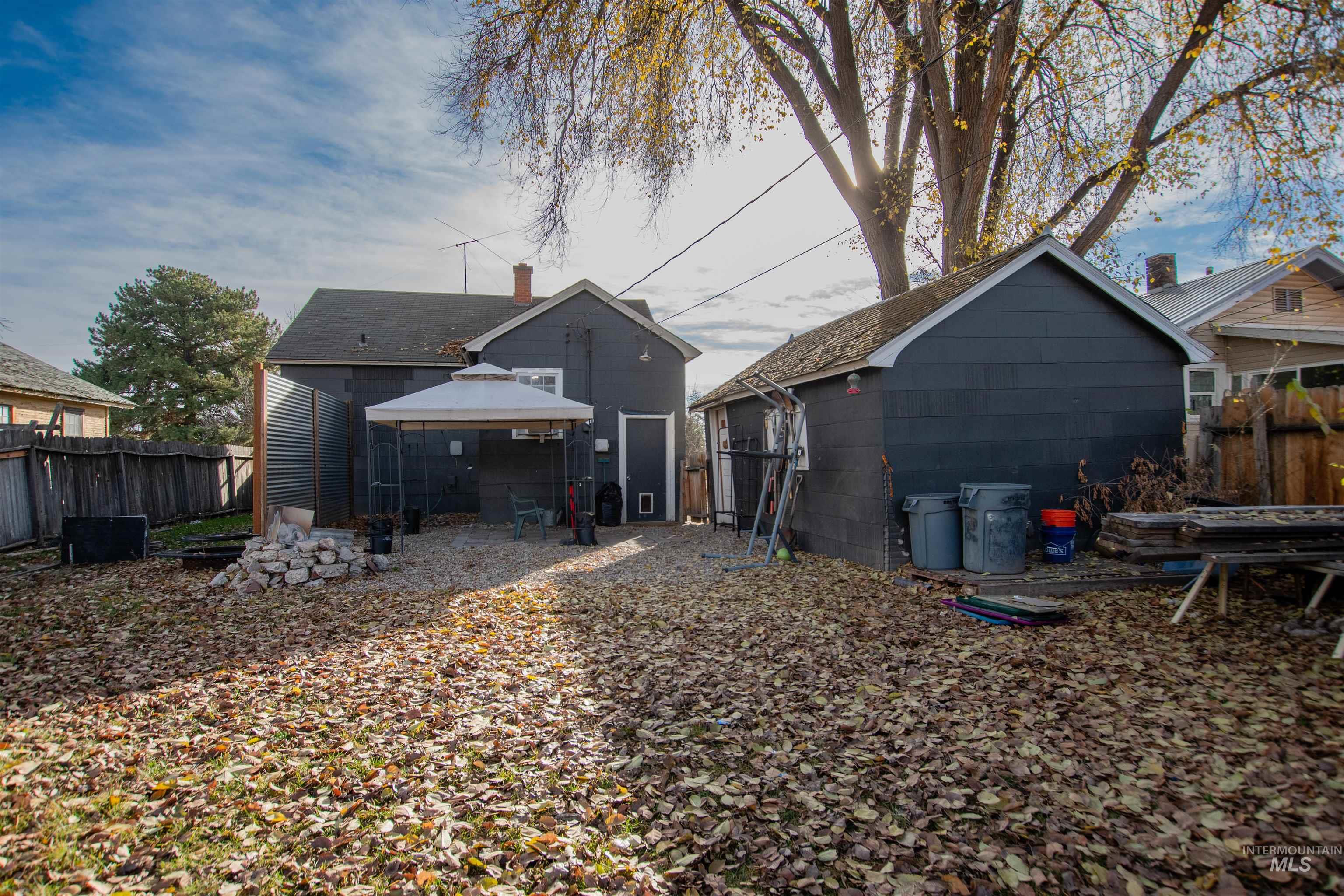 Back of house featuring a gazebo, concrete block siding, a chimney, an outdoor structure, and a patio