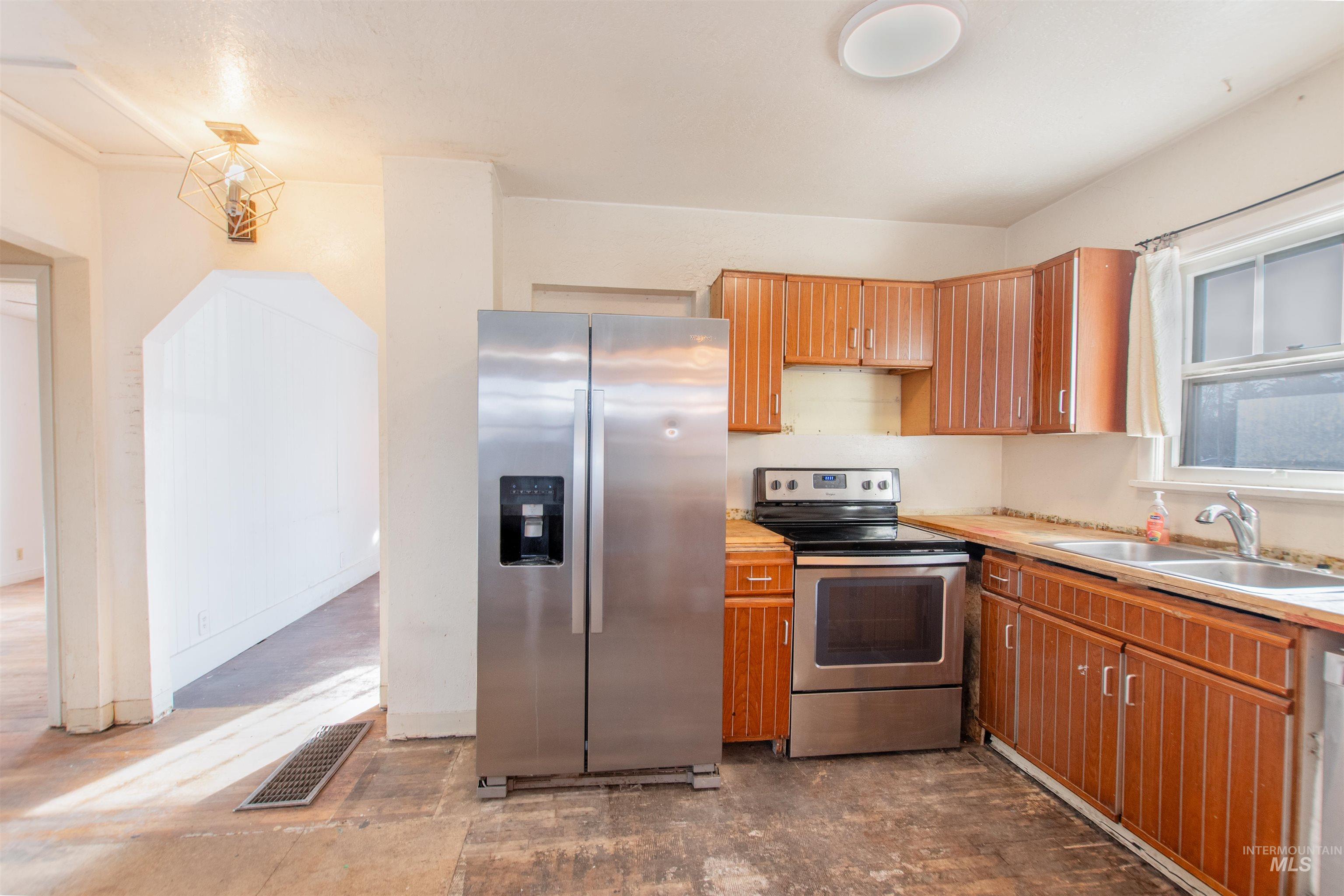 Kitchen featuring appliances with stainless steel finishes, light countertops, and brown cabinetry