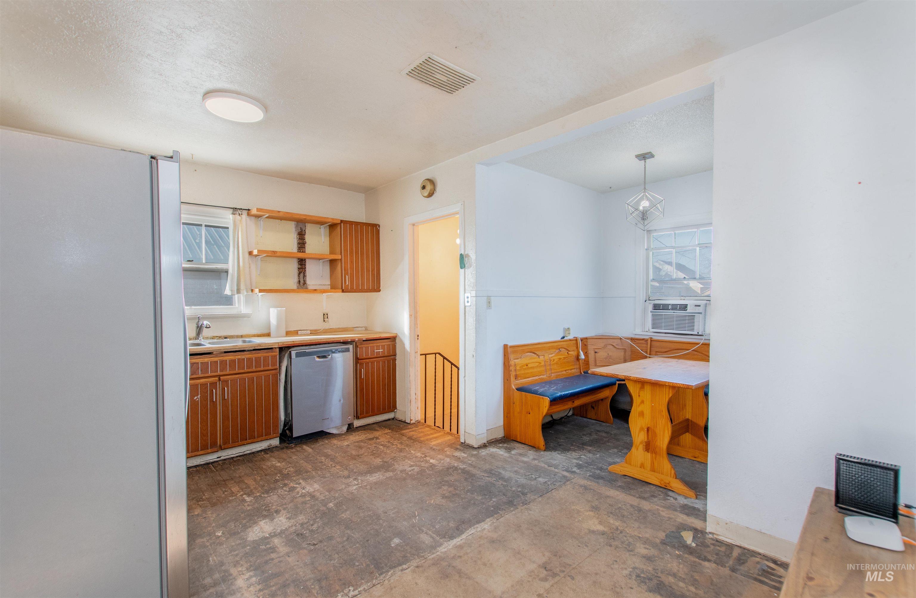 Kitchen with freestanding refrigerator, open shelves, light countertops, dishwasher, and brown cabinetry