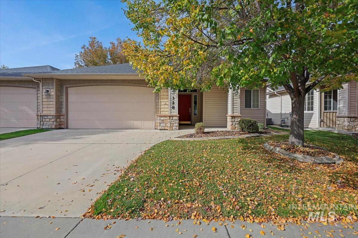 View of front of home with stone siding, driveway, a garage, and a shingled roof