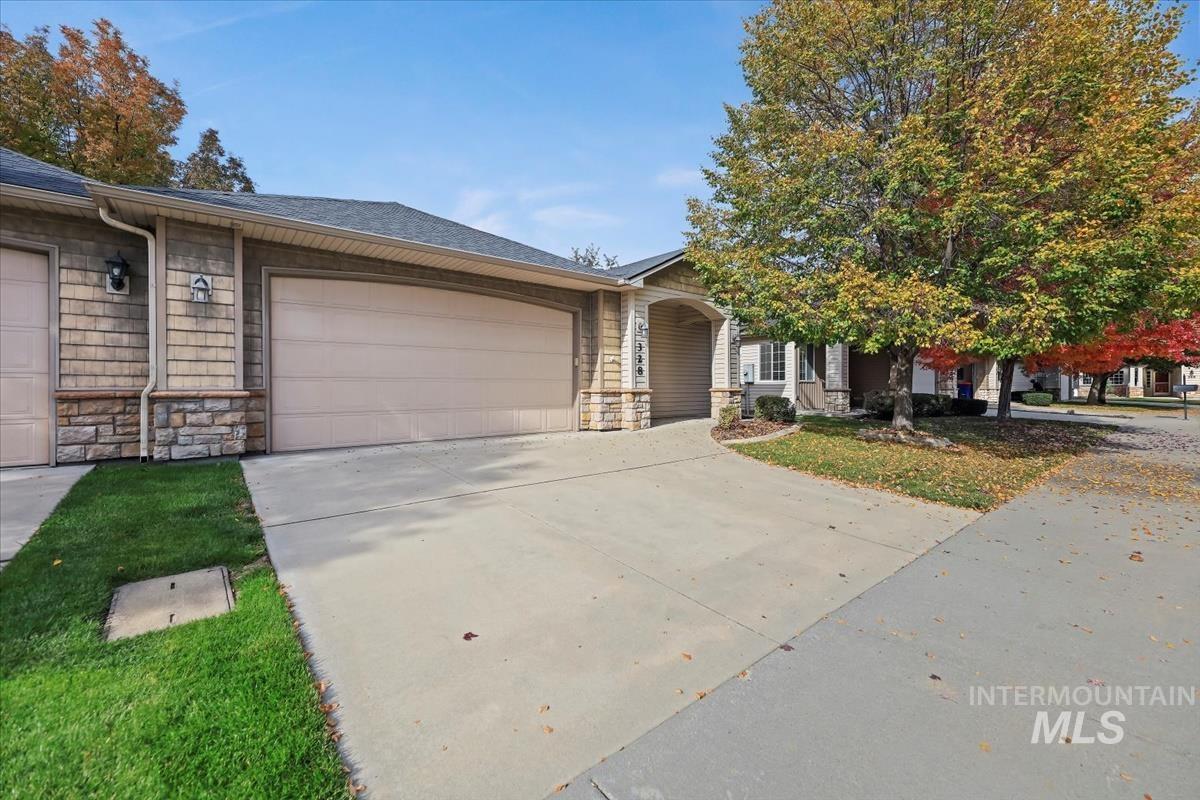View of front of home with stone siding, a shingled roof, concrete driveway, and a garage