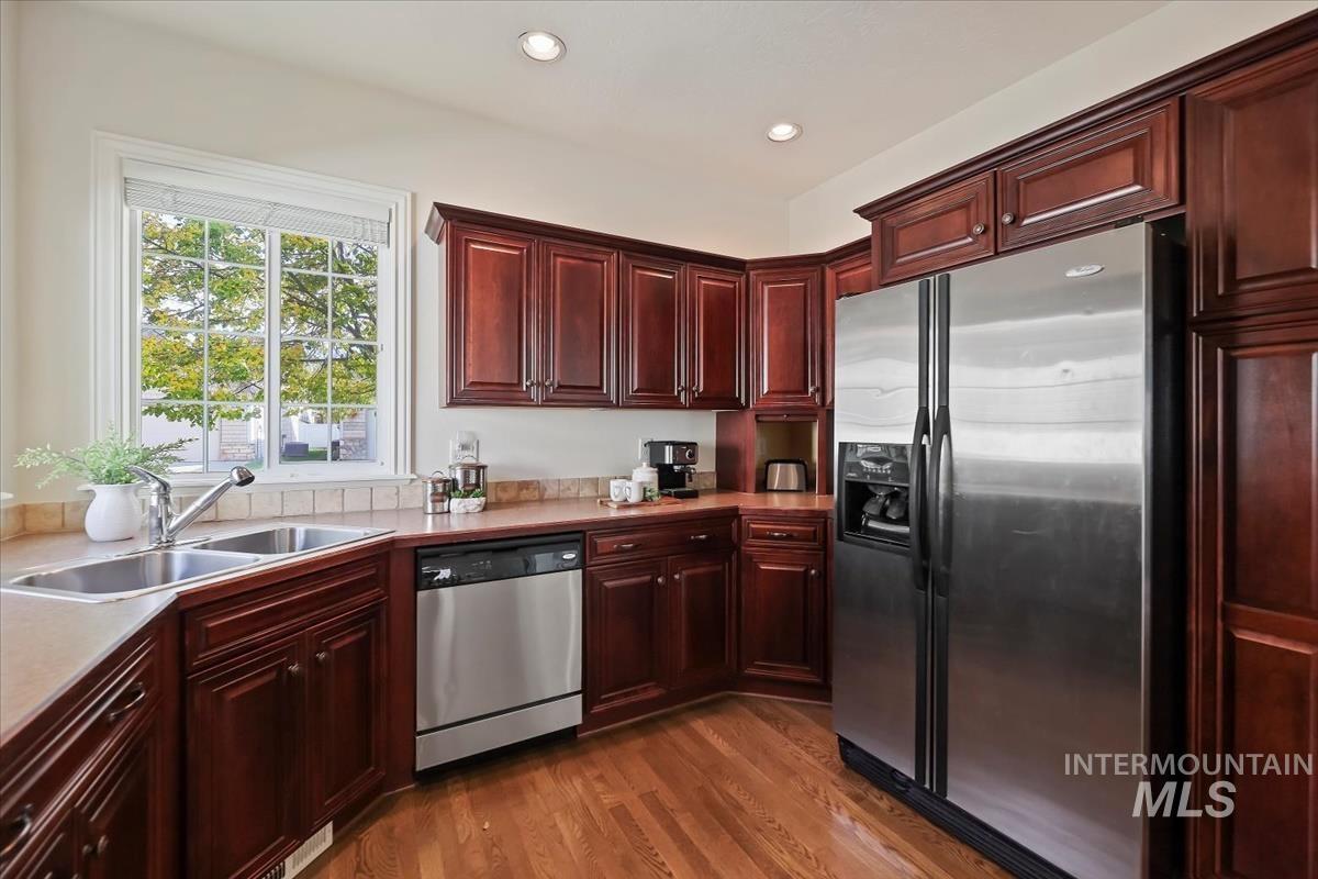 Kitchen featuring appliances with stainless steel finishes, light wood-style floors, dark brown cabinets, light countertops, and recessed lighting