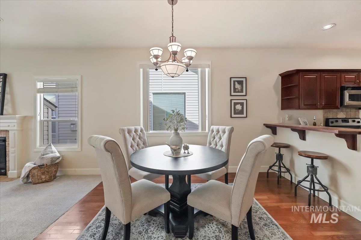 Dining room featuring dark wood-type flooring, recessed lighting, a chandelier, and a fireplace