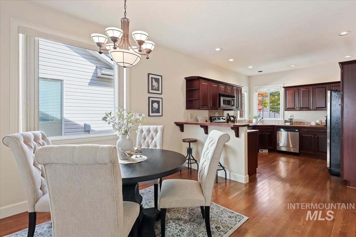 Dining area with dark wood finished floors, a chandelier, and recessed lighting