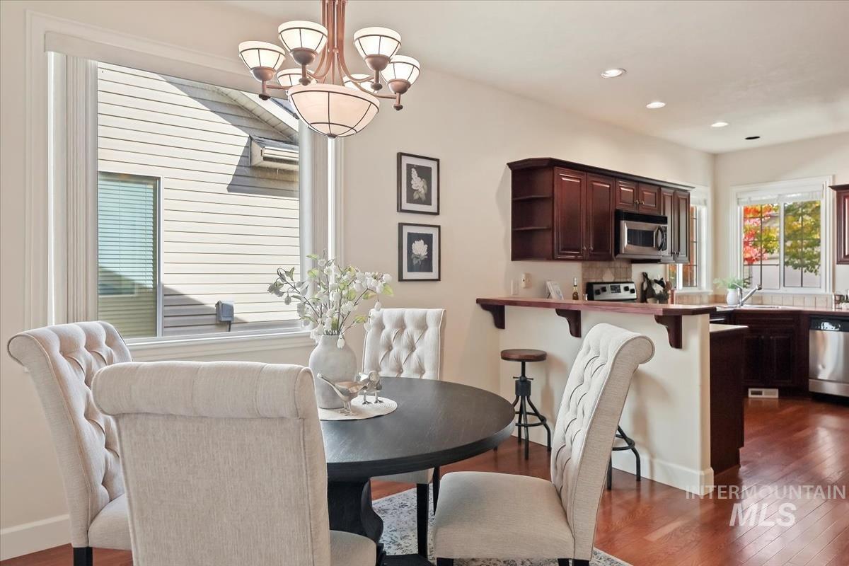 Dining space with dark wood-type flooring, a chandelier, and recessed lighting
