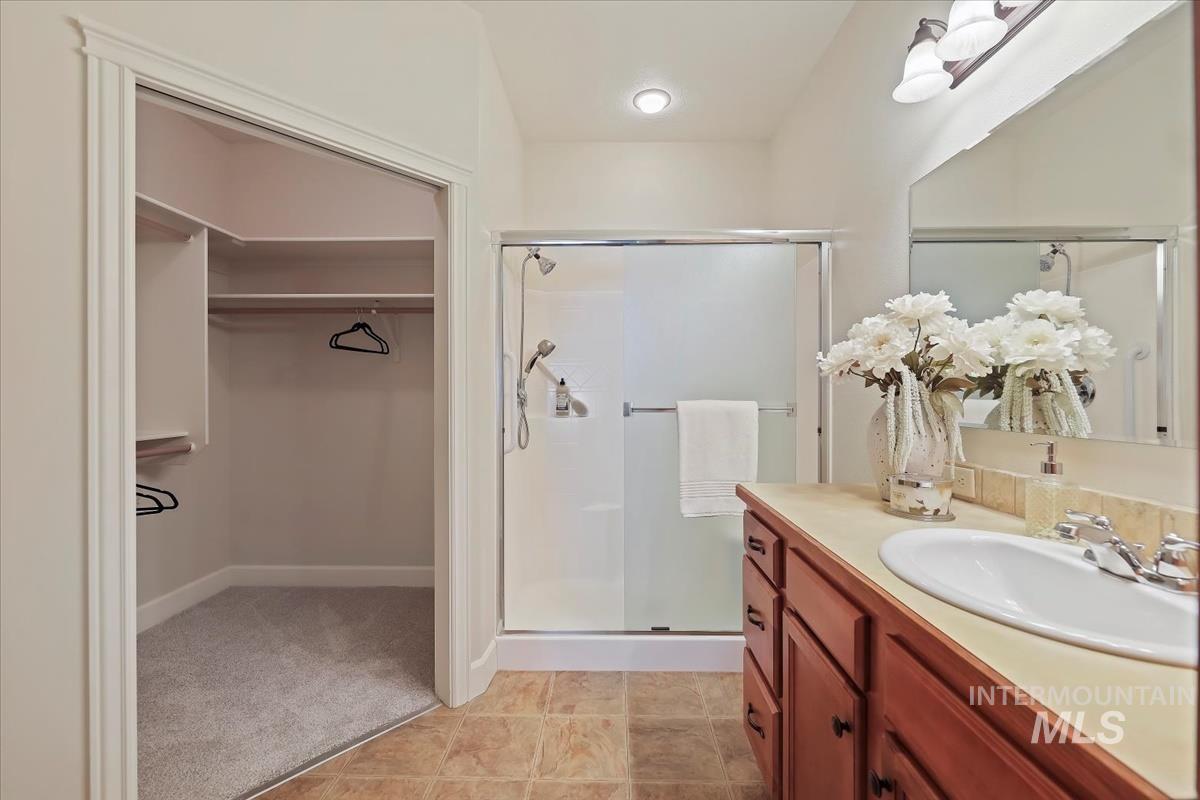 Bathroom featuring a spacious closet, vanity, a stall shower, and light carpet