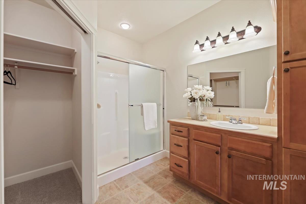 Full bathroom with vanity, a stall shower, and a walk in closet