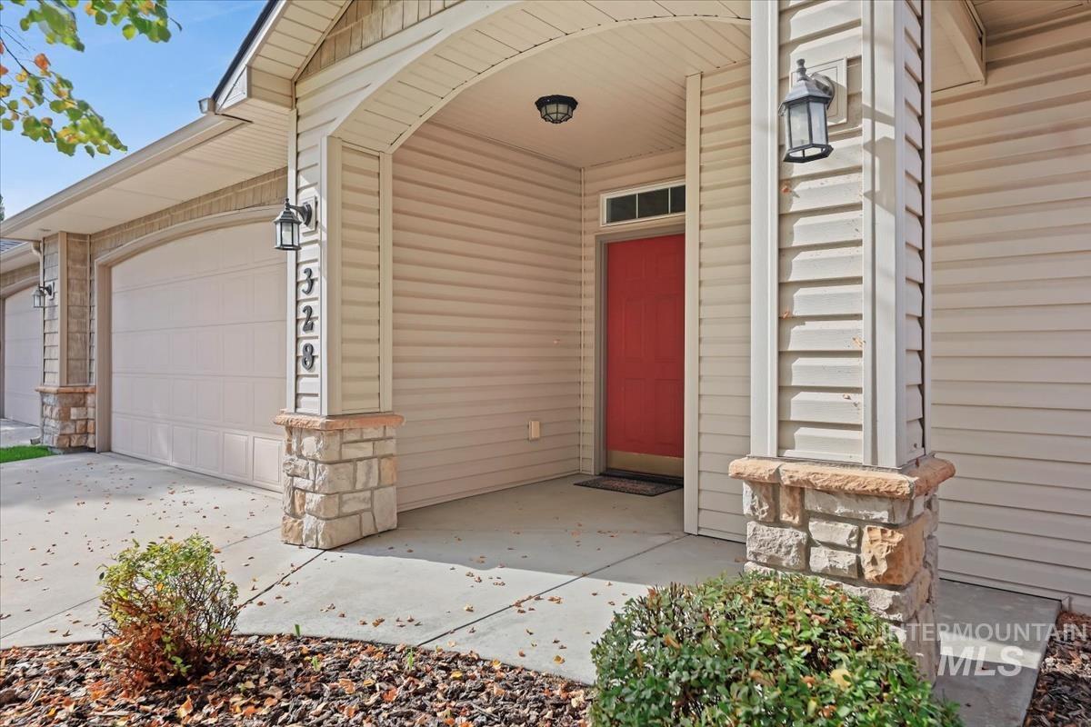 View of exterior entry featuring a porch, stone siding, concrete driveway, and a garage