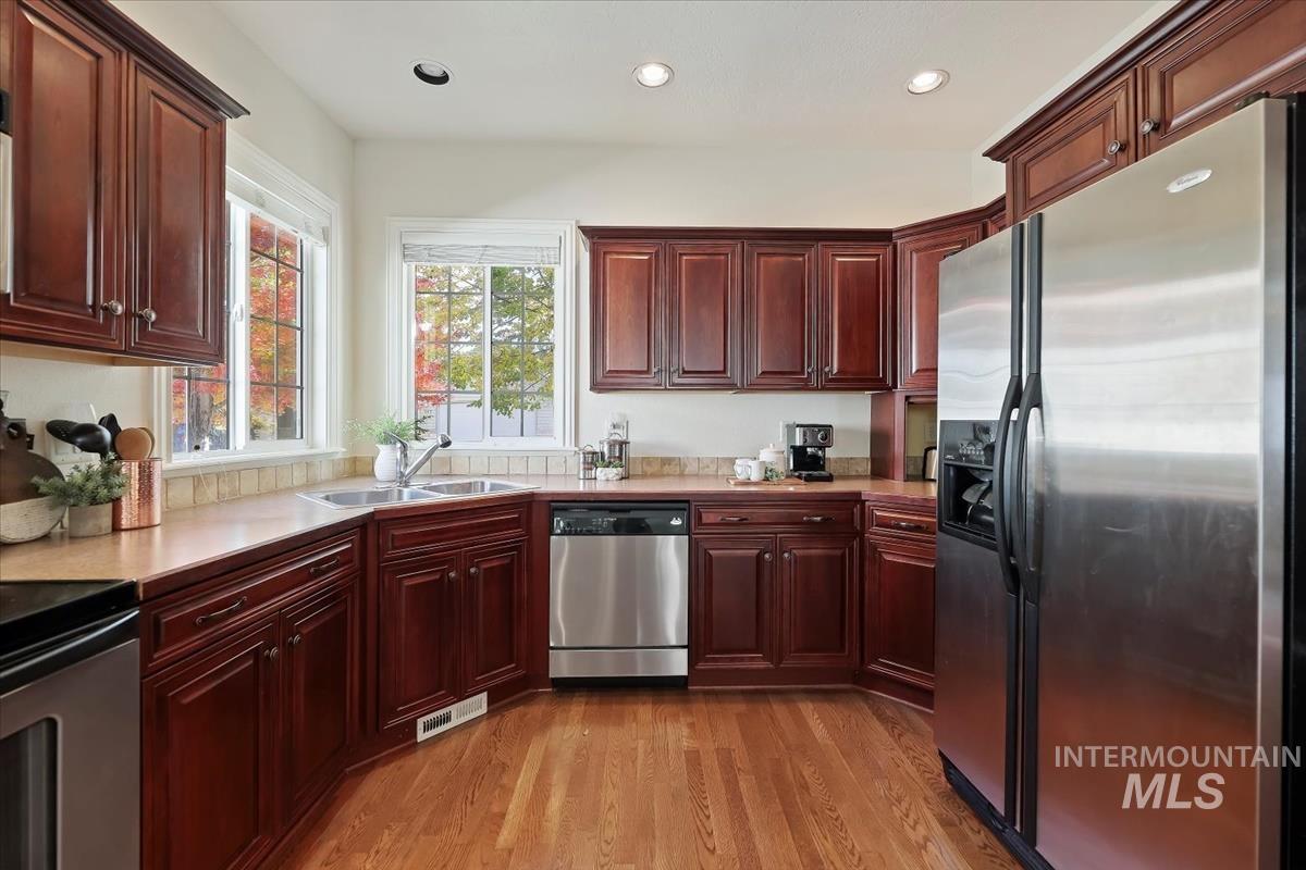 Kitchen featuring appliances with stainless steel finishes, light wood-style flooring, reddish brown cabinets, light countertops, and recessed lighting