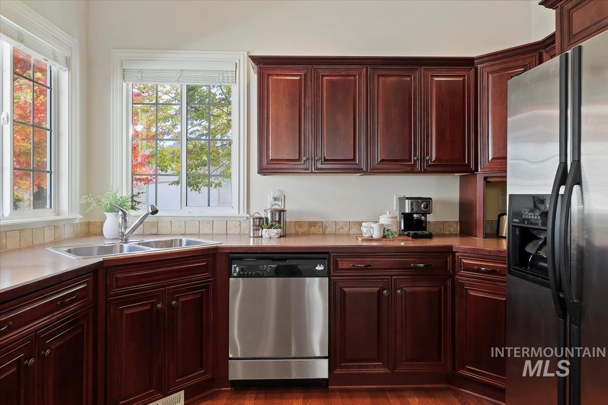 Kitchen featuring appliances with stainless steel finishes, dark brown cabinets, light countertops, and dark wood-style floors