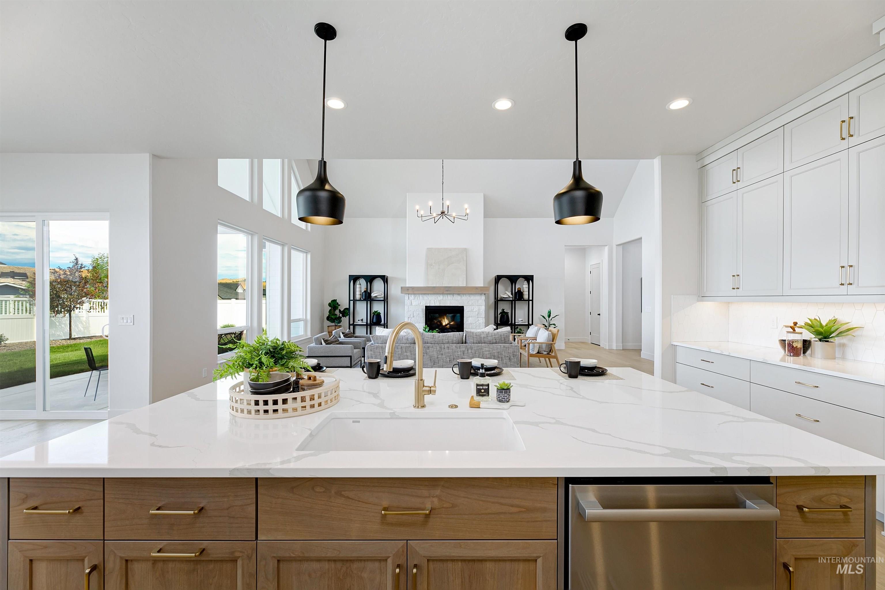 Kitchen with dishwasher, open floor plan, a chandelier, light stone countertops, and hanging light fixtures