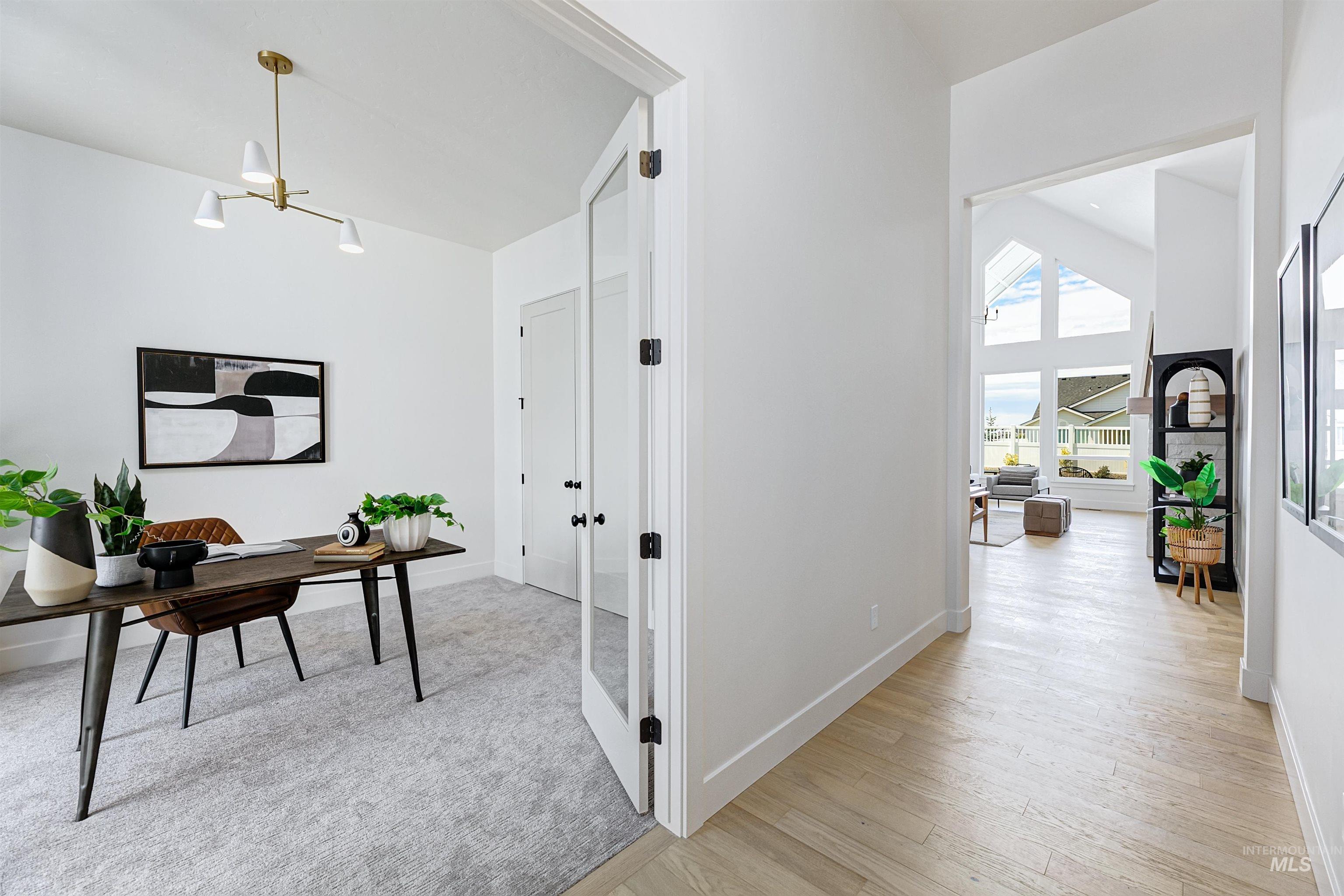 Home office with a chandelier, light wood-style flooring, and a towering ceiling
