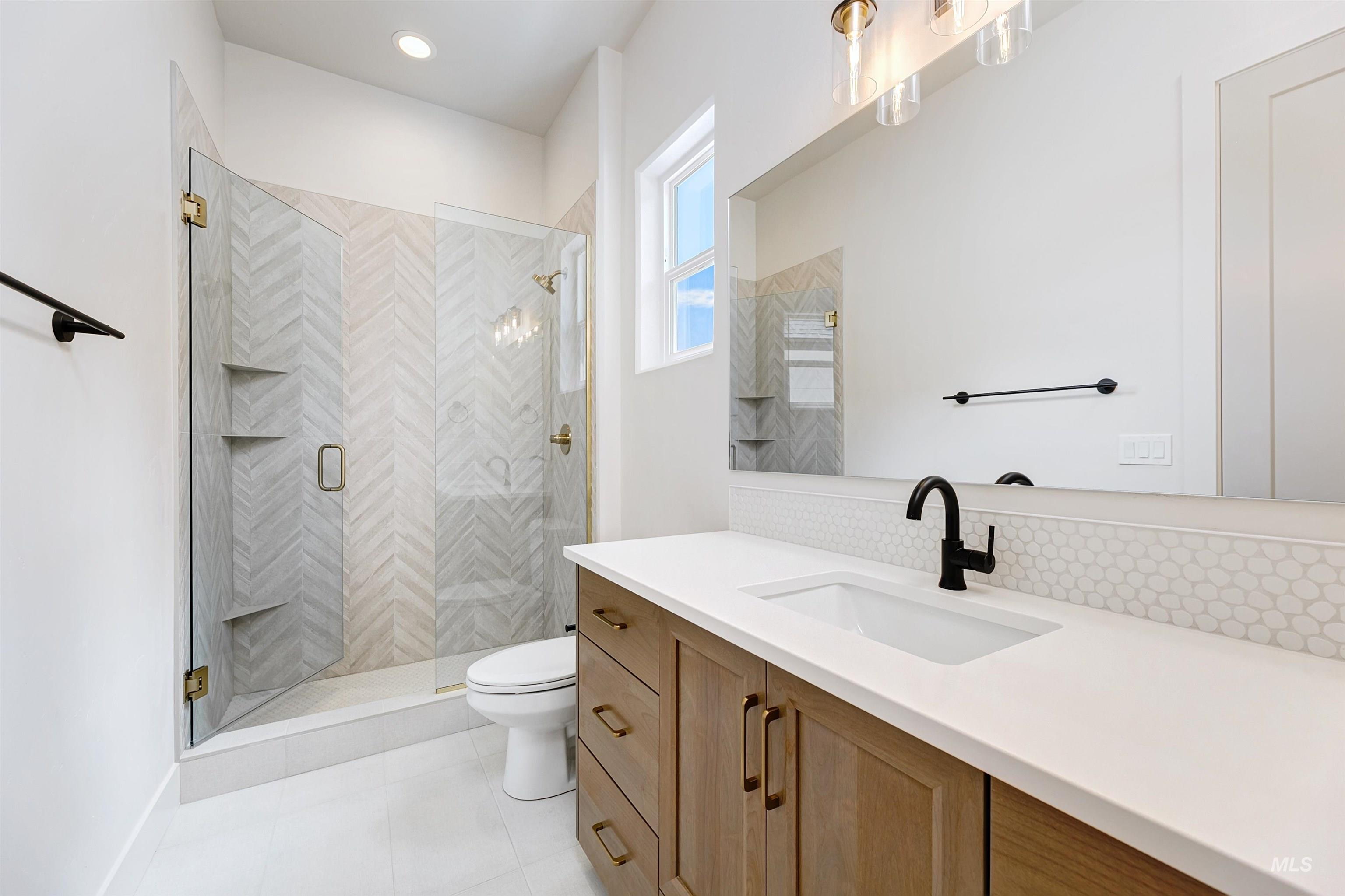 Full bath with vanity, a stall shower, and light tile patterned flooring
