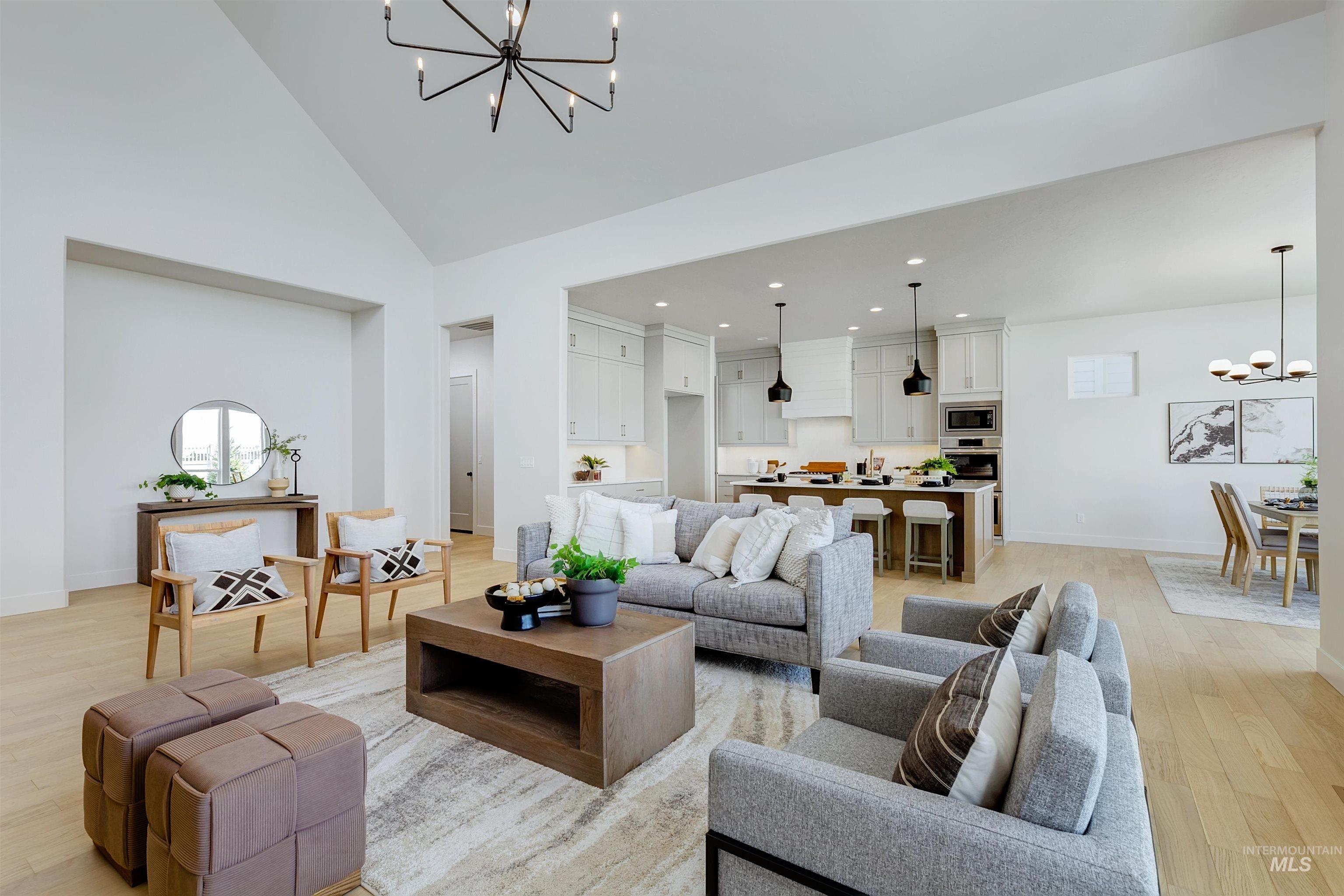 Living area with a chandelier, light wood-style floors, high vaulted ceiling, and recessed lighting