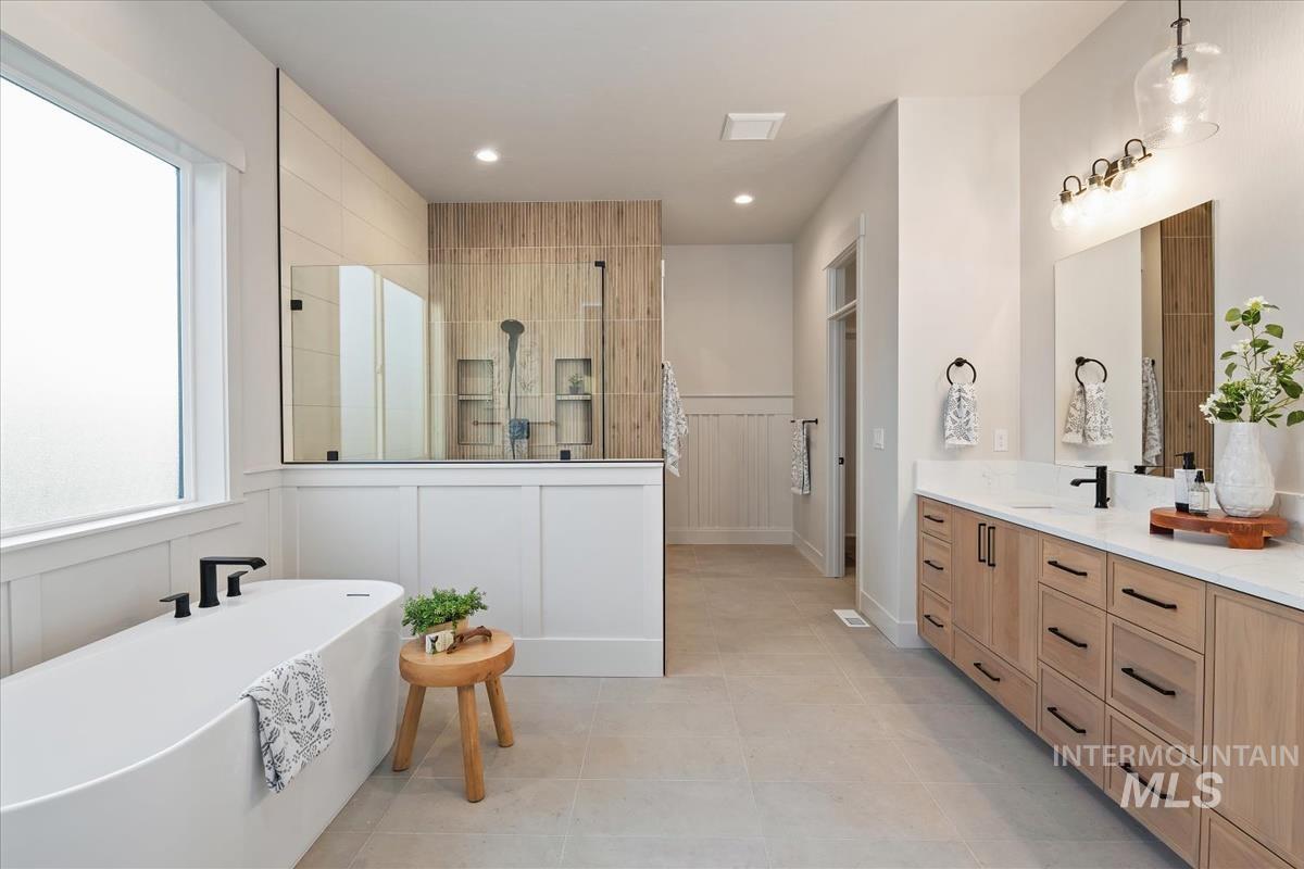 Full bath with a soaking tub, healthy amount of natural light, a decorative wall, a walk in shower, and vanity