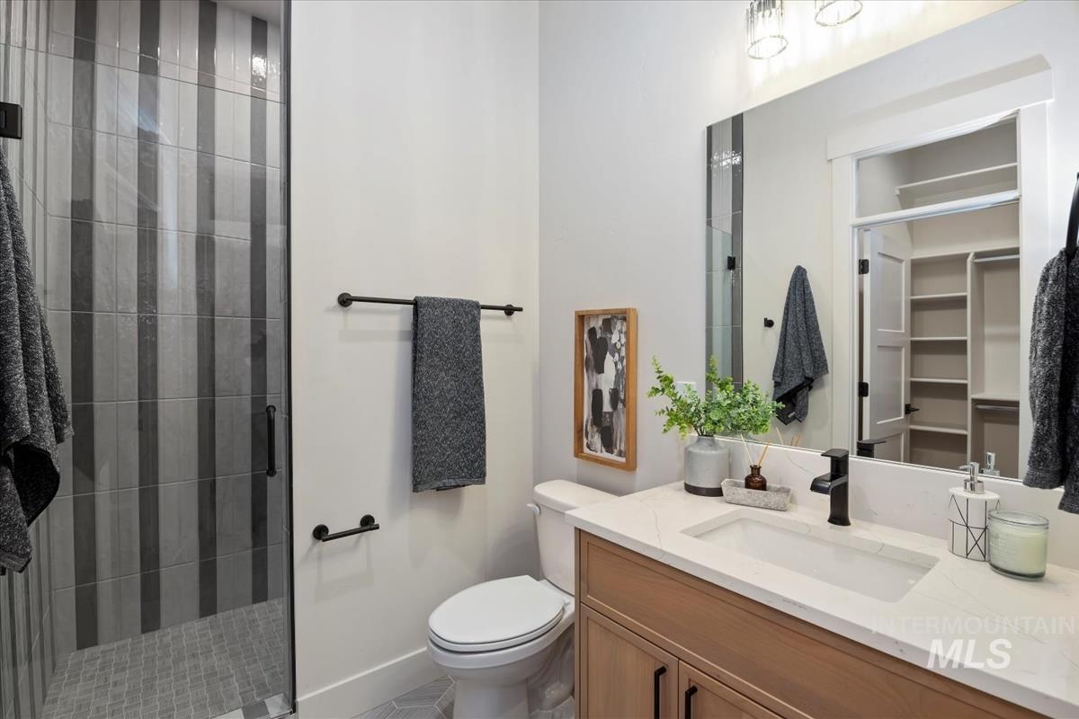 Full bathroom with vanity, a stall shower, and a walk in closet