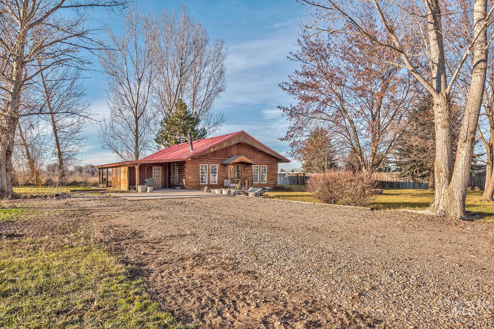 View of front of home featuring a metal roof, log exterior, and a patio area