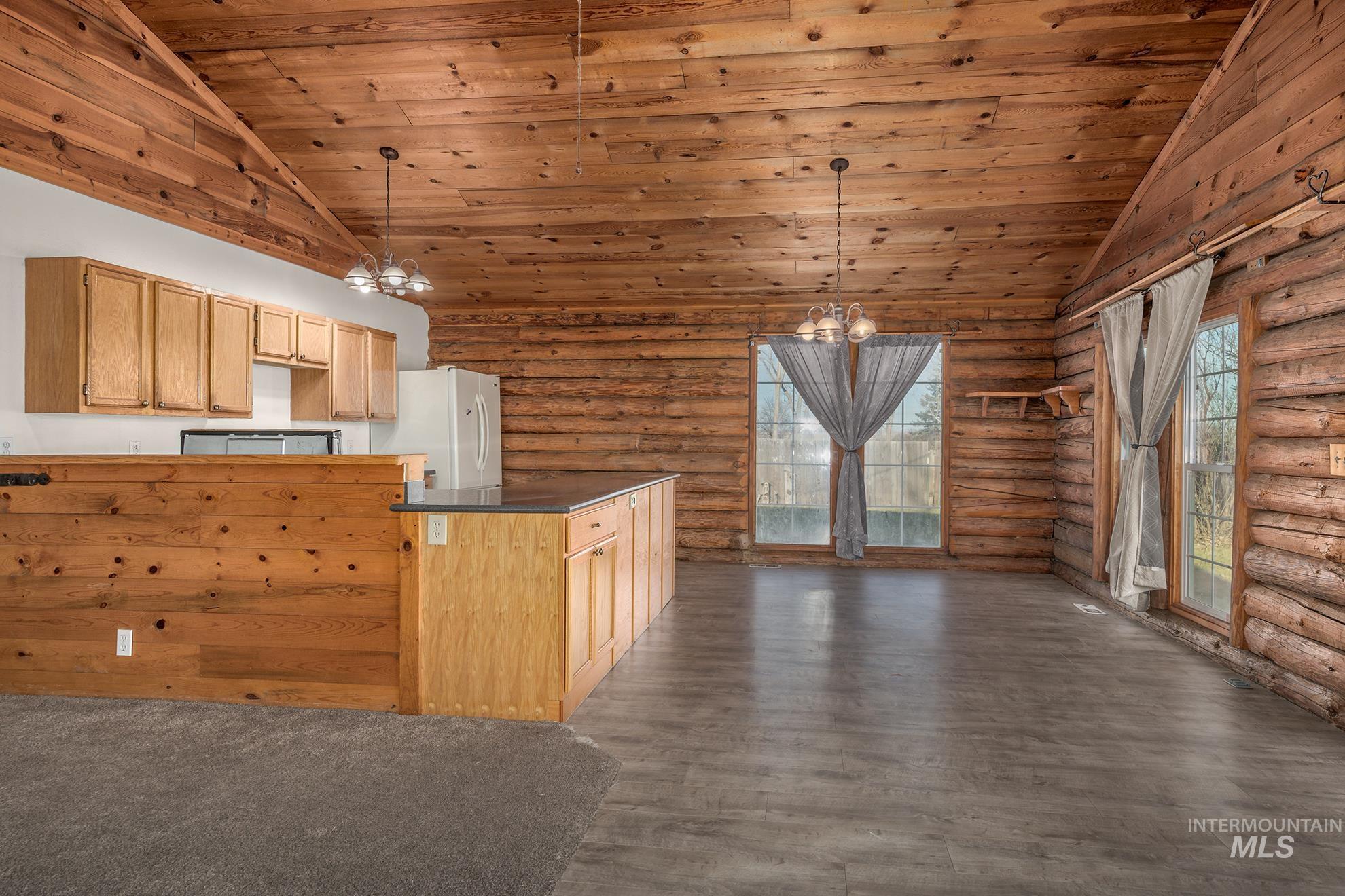 Kitchen with a chandelier, wood ceiling, dark countertops, plenty of natural light, and log walls