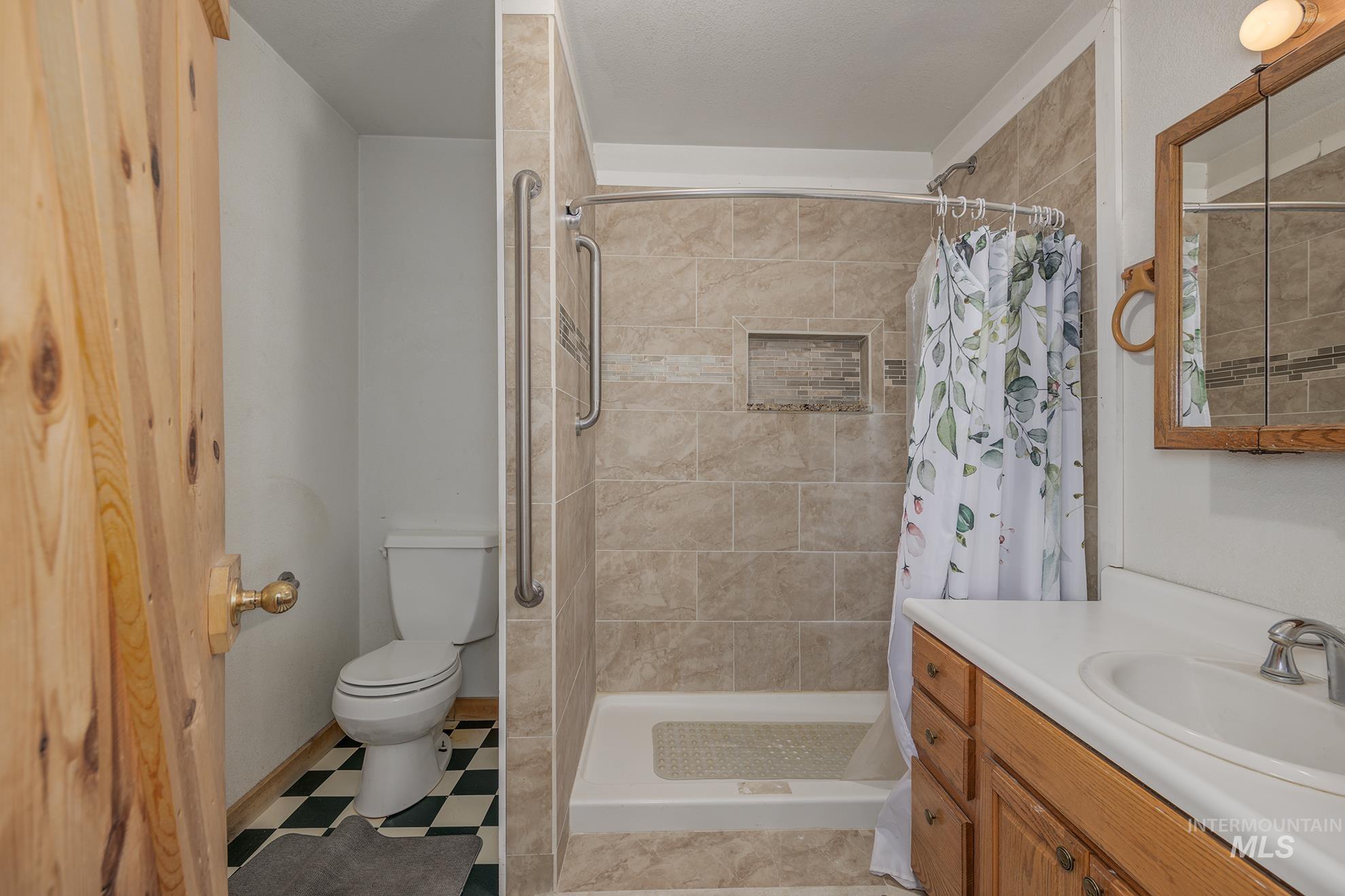 Full bath featuring vanity, a shower stall, and light floors