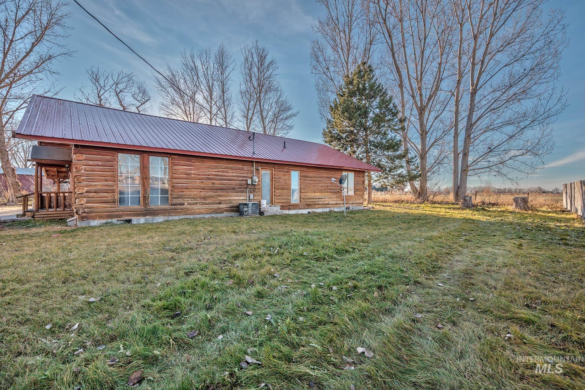Back of house with a metal roof, a lawn, and log exterior