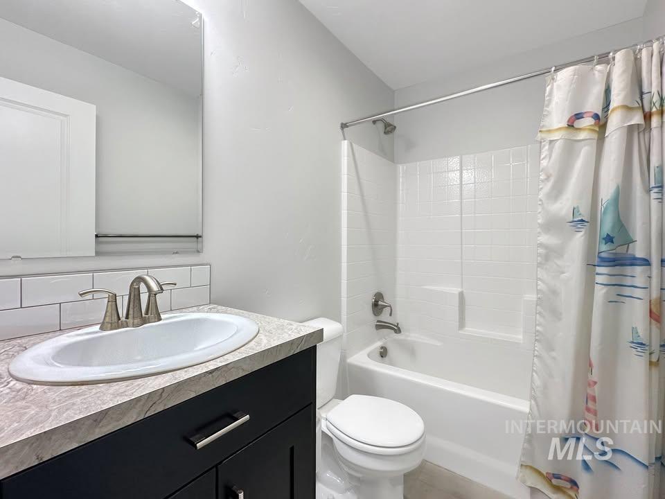 Bathroom with shower / bath combo, vanity, and tasteful backsplash