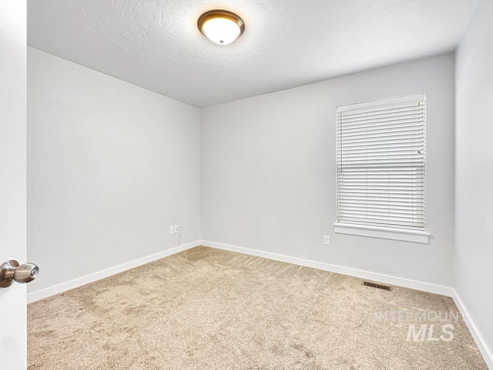 Unfurnished room with light colored carpet and a textured ceiling