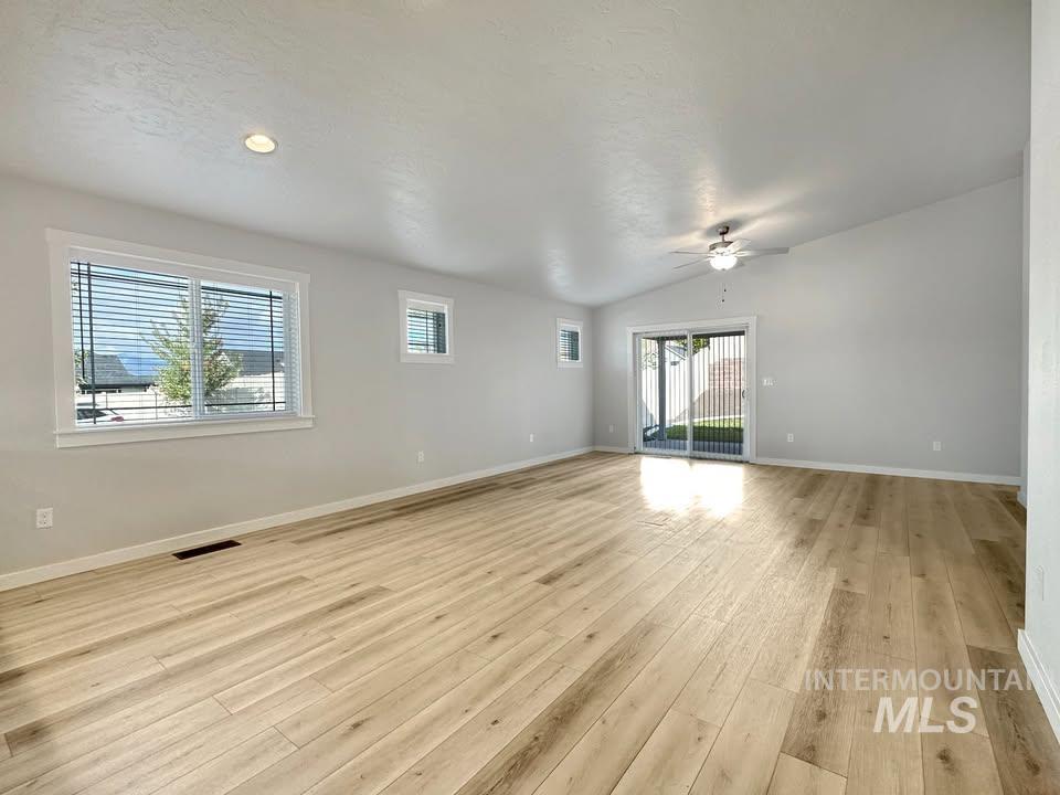 Spare room with light wood finished floors, ceiling fan, and lofted ceiling
