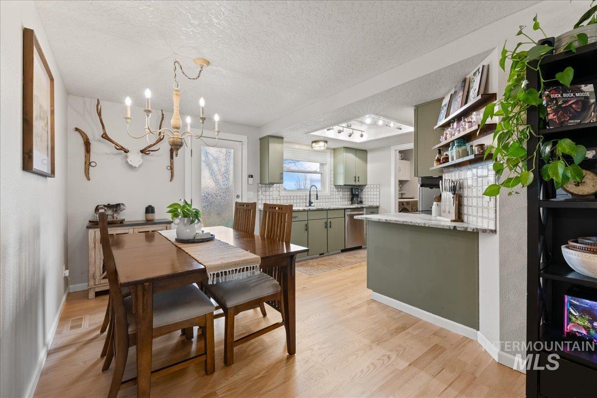Dining room with a textured ceiling, a chandelier, and light wood-style floors