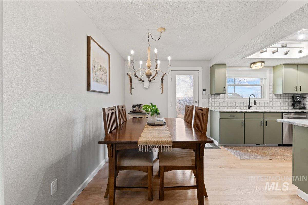 Dining space featuring a chandelier, light wood-type flooring, and a textured ceiling