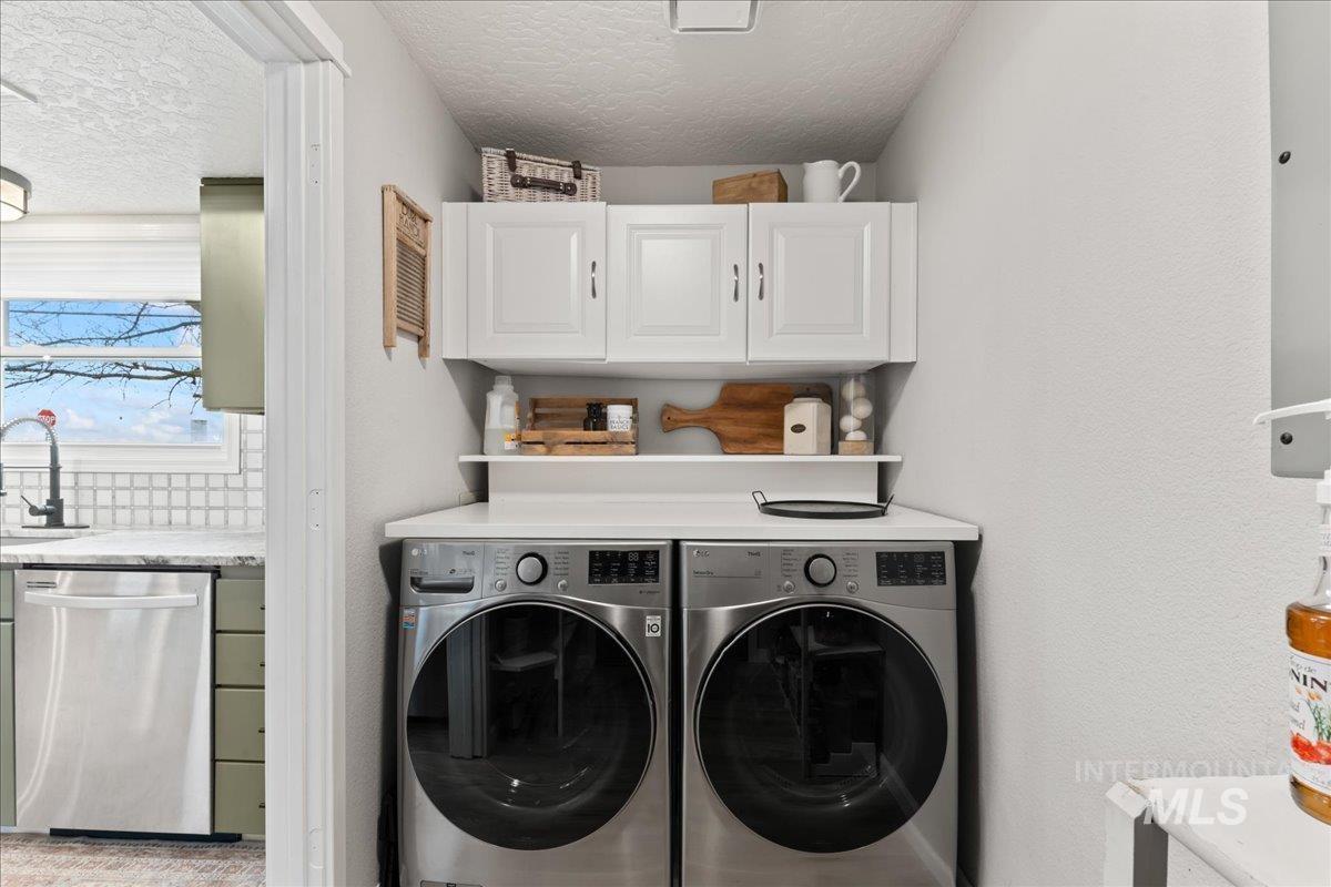 Washroom featuring a textured ceiling, separate washer and dryer, and cabinet space