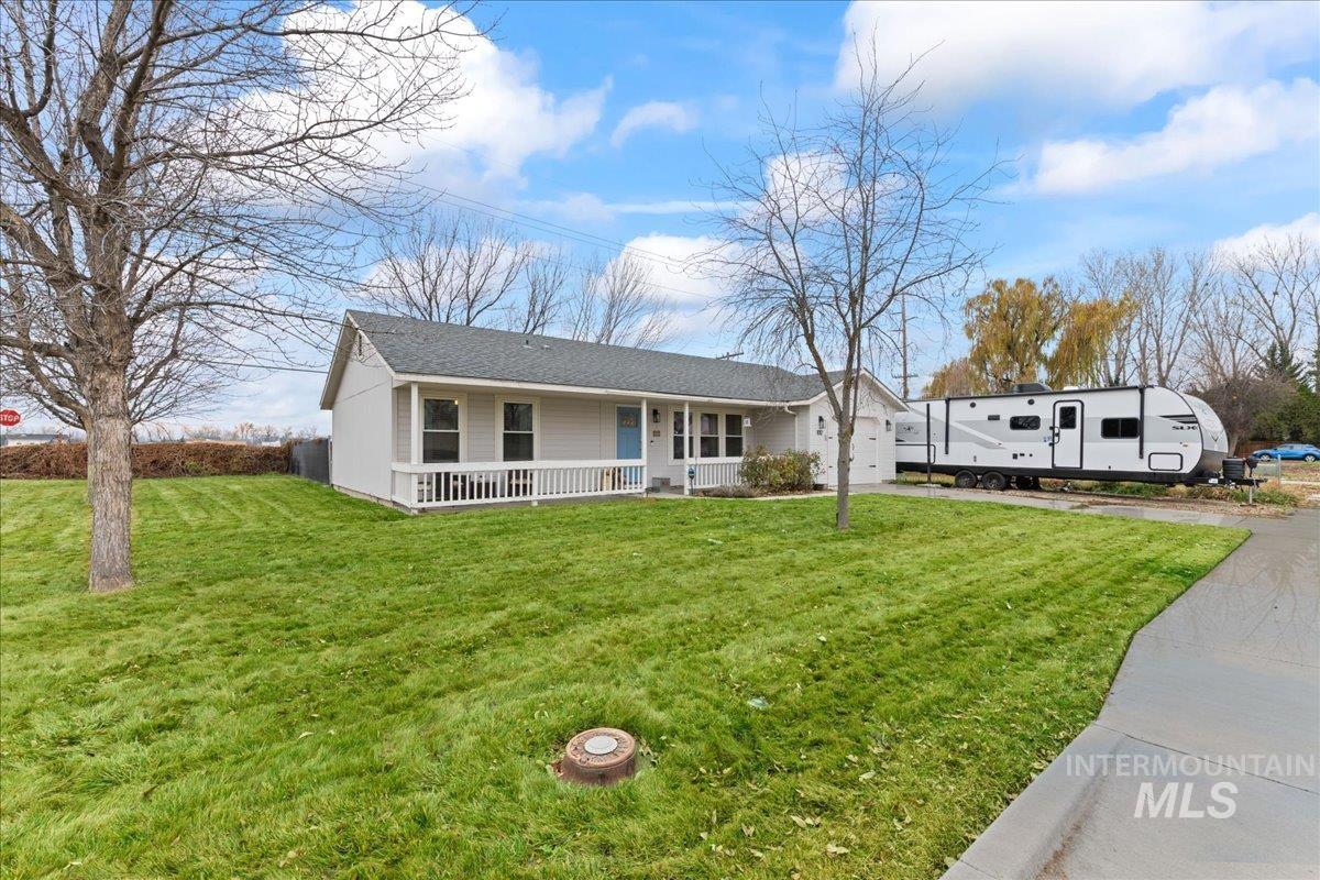 View of front facade featuring a porch, a front yard, driveway, and roof with shingles