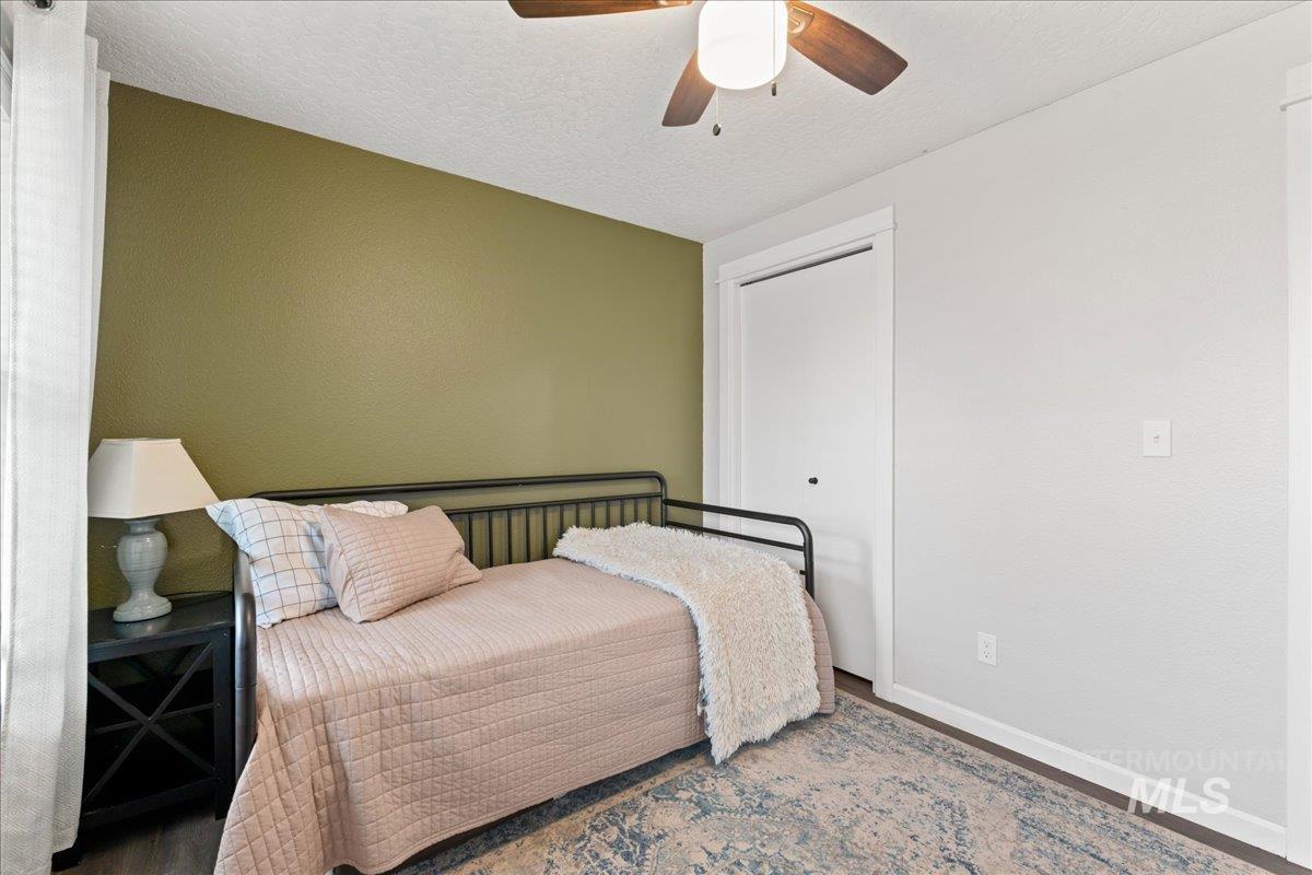 Bedroom featuring wood finished floors, a closet, a ceiling fan, and a textured ceiling