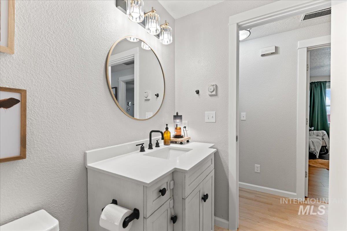 Half bath with a textured wall, vanity, and light wood-style floors