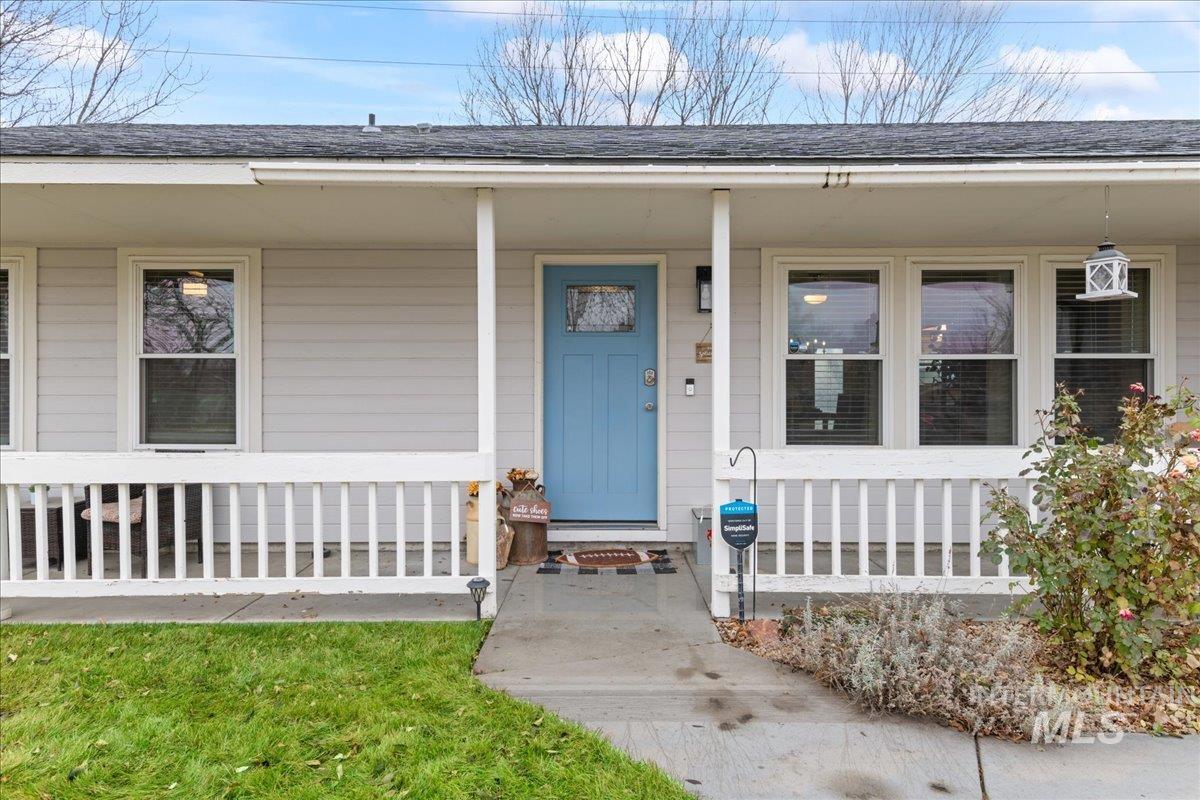 Doorway to property featuring a porch and roof with shingles