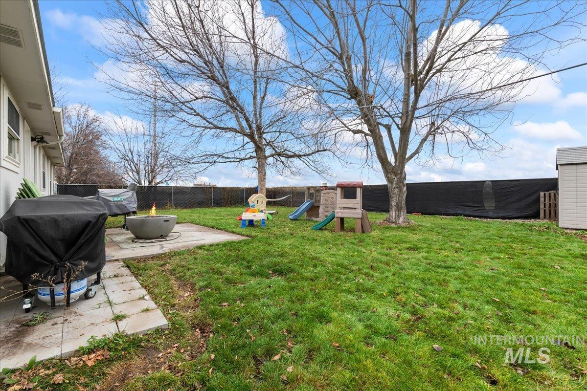 Fenced backyard featuring a patio, a playground, and an outdoor fire pit