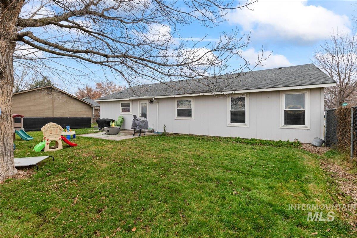 Back of house featuring a shingled roof, a patio, and a playground