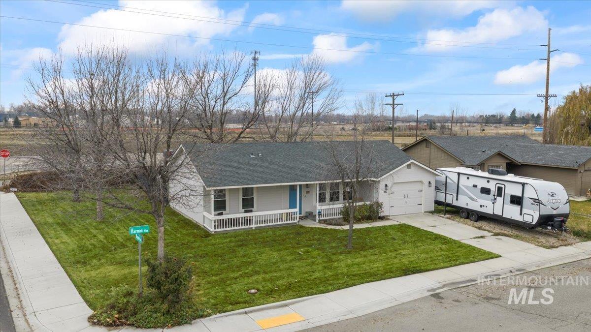 View of front of house with a porch, a front yard, driveway, a shingled roof, and an attached garage