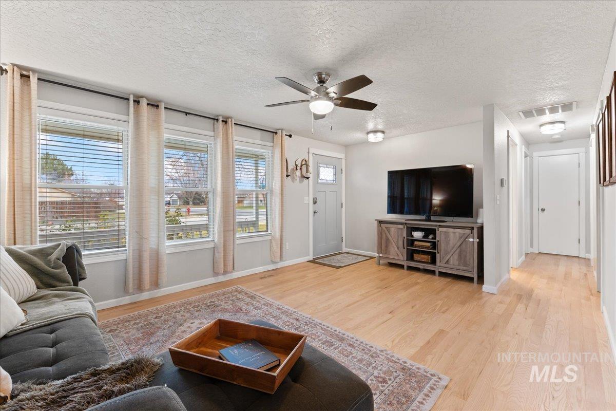 Living room featuring a textured ceiling, light wood-style floors, and a ceiling fan