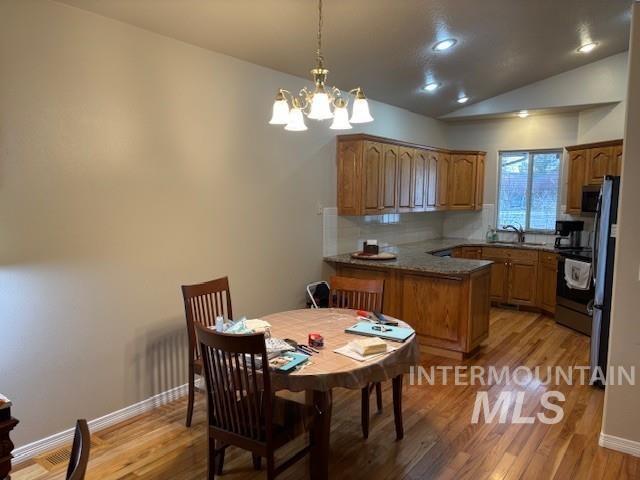 Dining room featuring vaulted ceiling, light wood-type flooring, a chandelier, and recessed lighting
