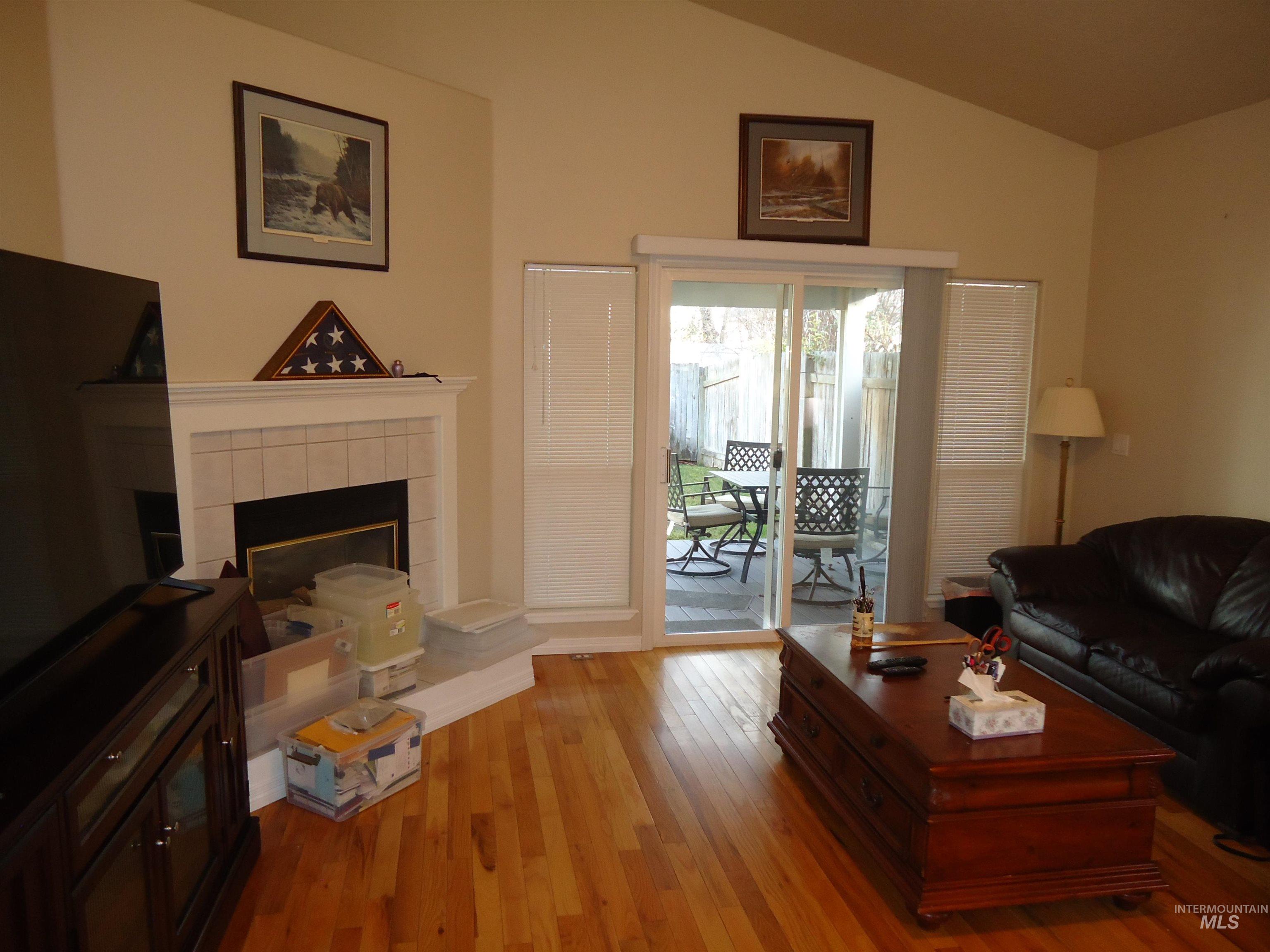 Living area with light wood-type flooring, a tile fireplace, and lofted ceiling