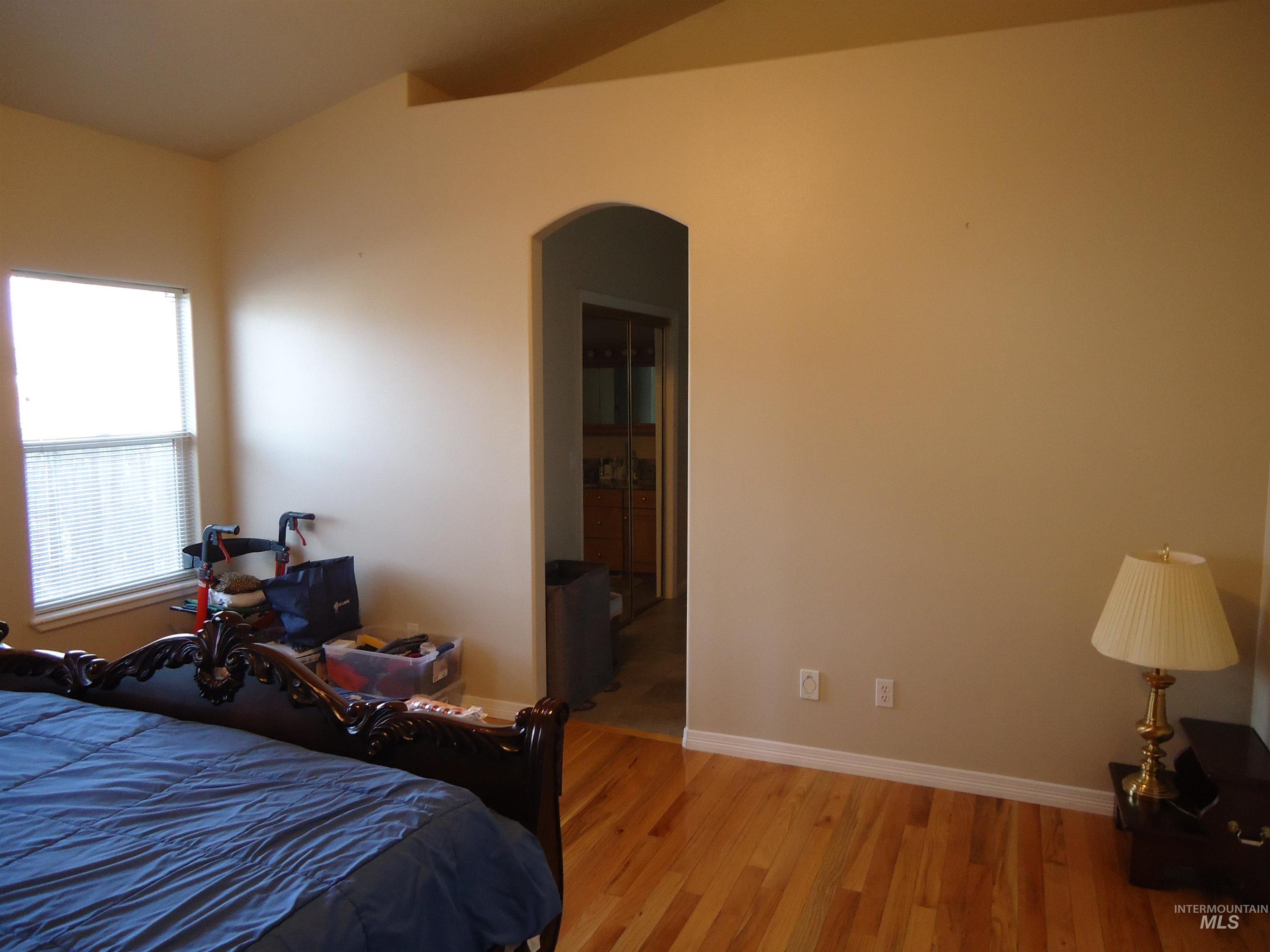 Bedroom with arched walkways and wood finished floors