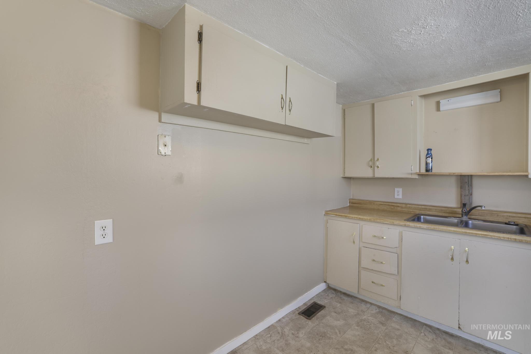 Kitchen featuring a textured ceiling, light countertops, and cream cabinetry