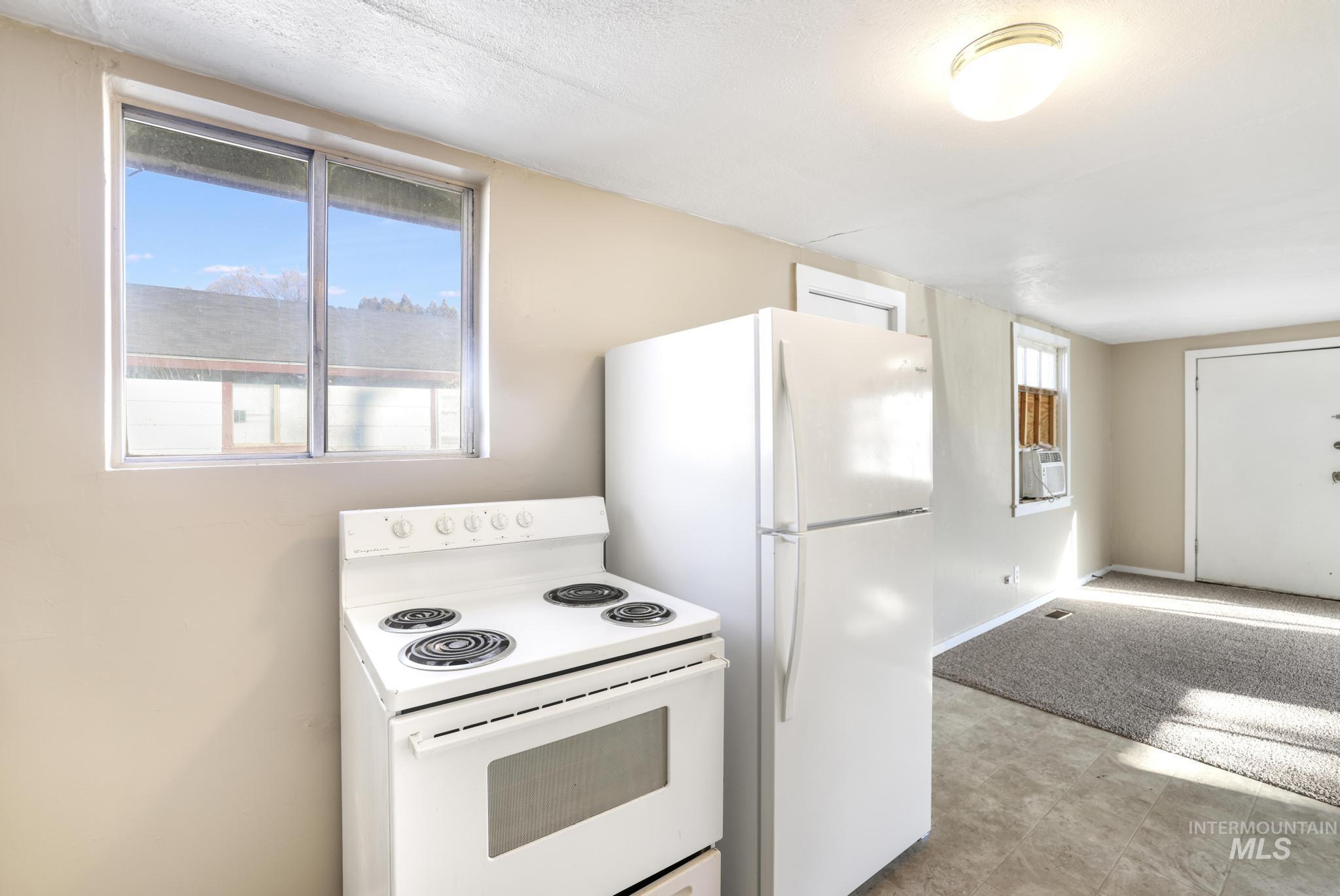 Kitchen with white range with electric stovetop, a textured ceiling, and light flooring