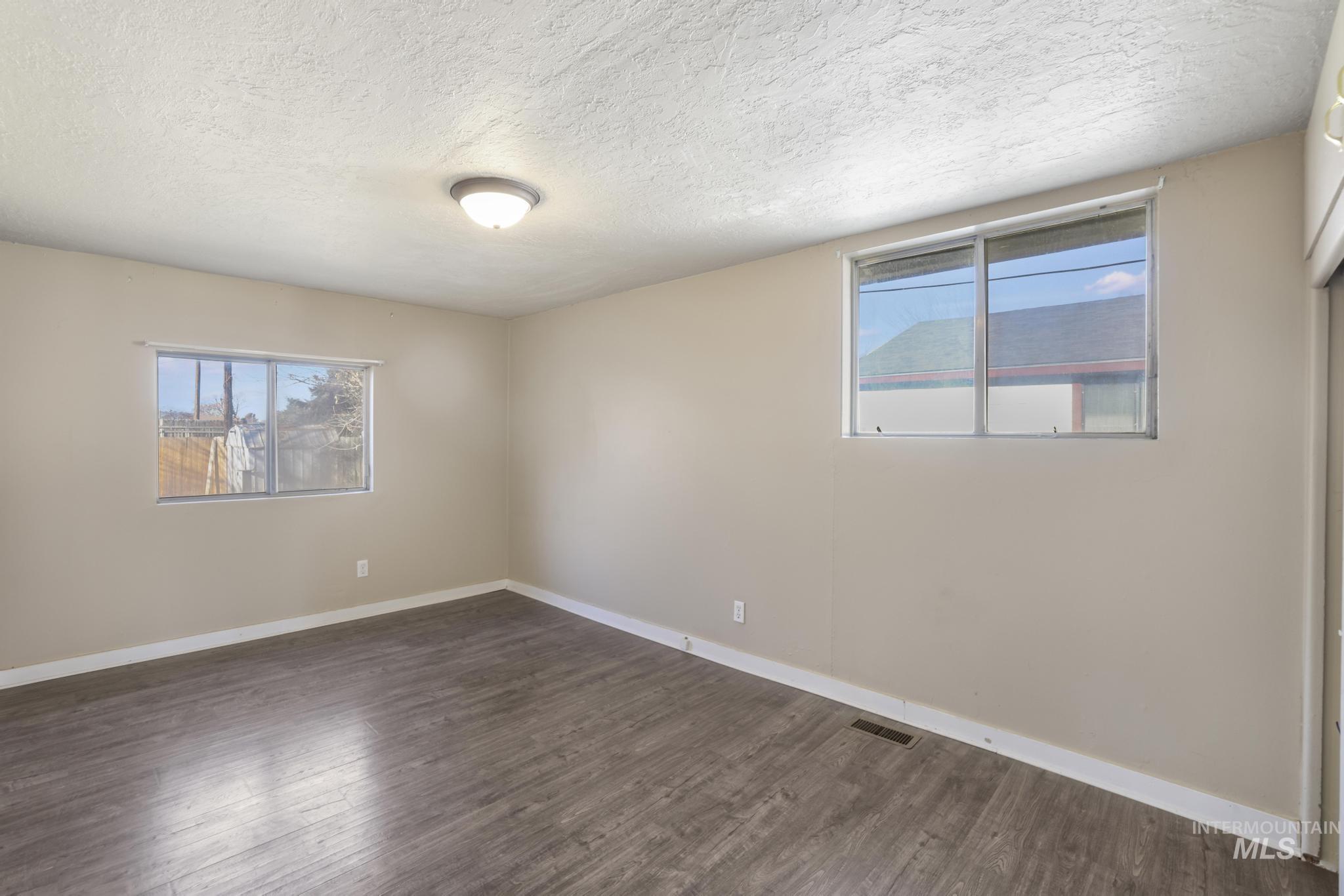 Unfurnished room featuring a textured ceiling and dark wood-style floors
