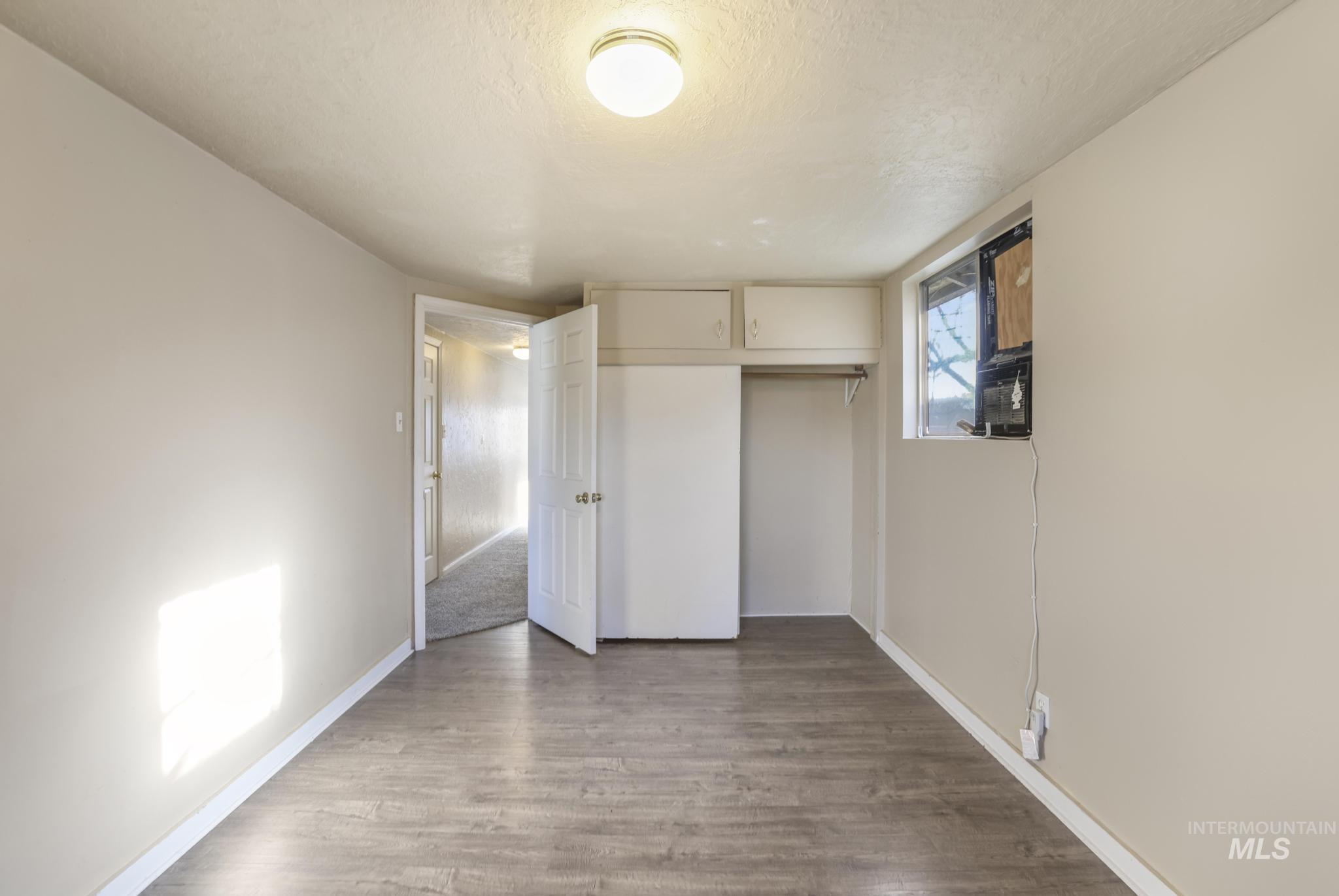 Unfurnished bedroom with a textured ceiling, a closet, and light wood-style flooring