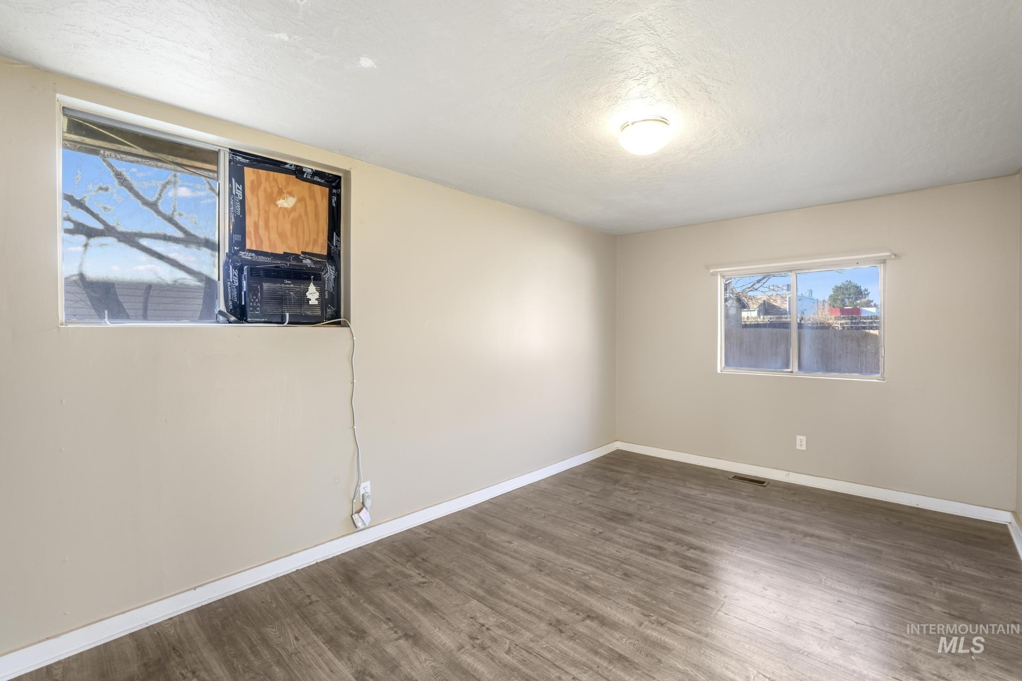 Unfurnished room featuring healthy amount of natural light, wood finished floors, and a textured ceiling